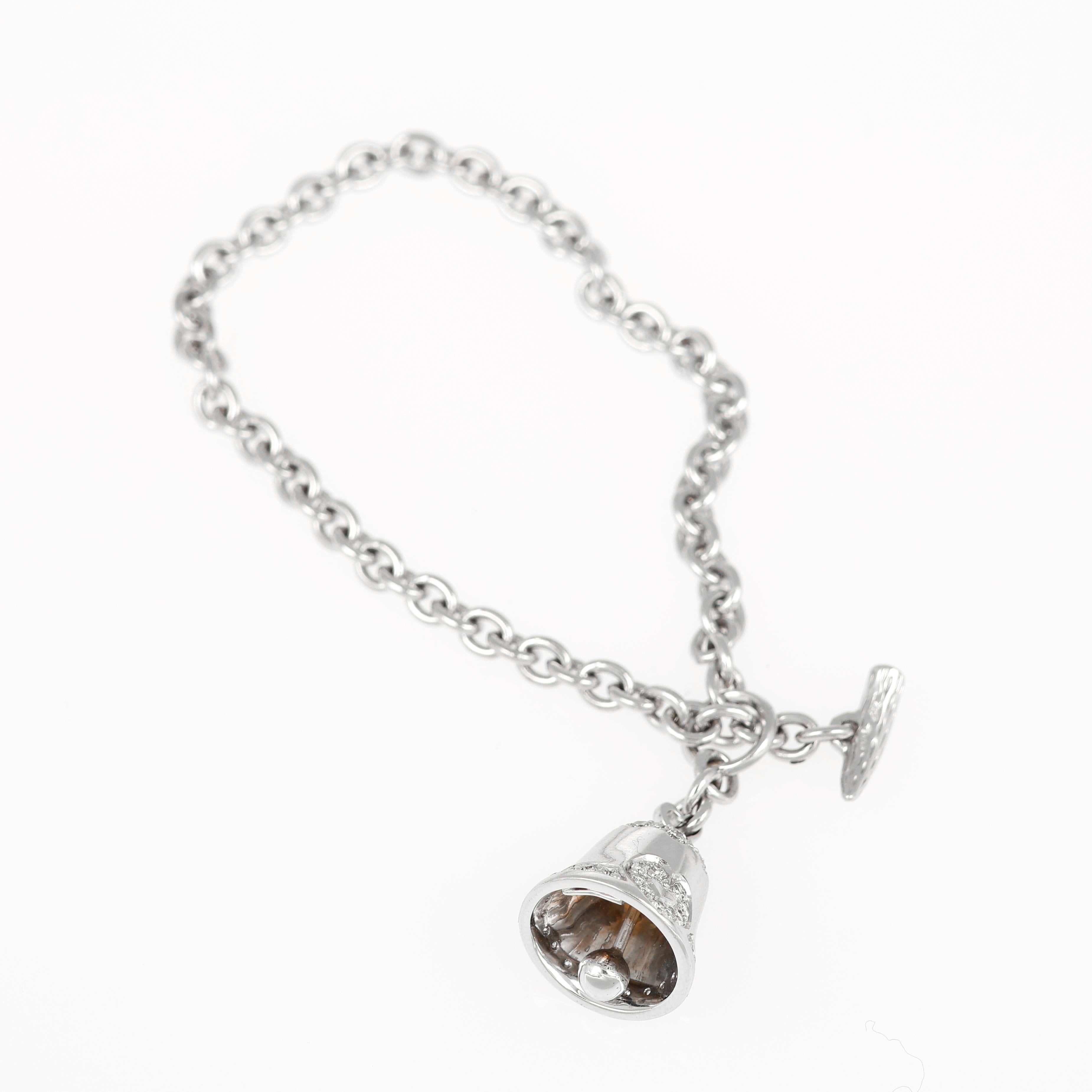An elegant bracelet crafted in 18K white gold, featuring a delicate bell charm adorned with a heart motif in pavé-set natural white diamonds totaling 0.57 carats. The refined chain and intricate charm design create a timeless and symbolic piece,
