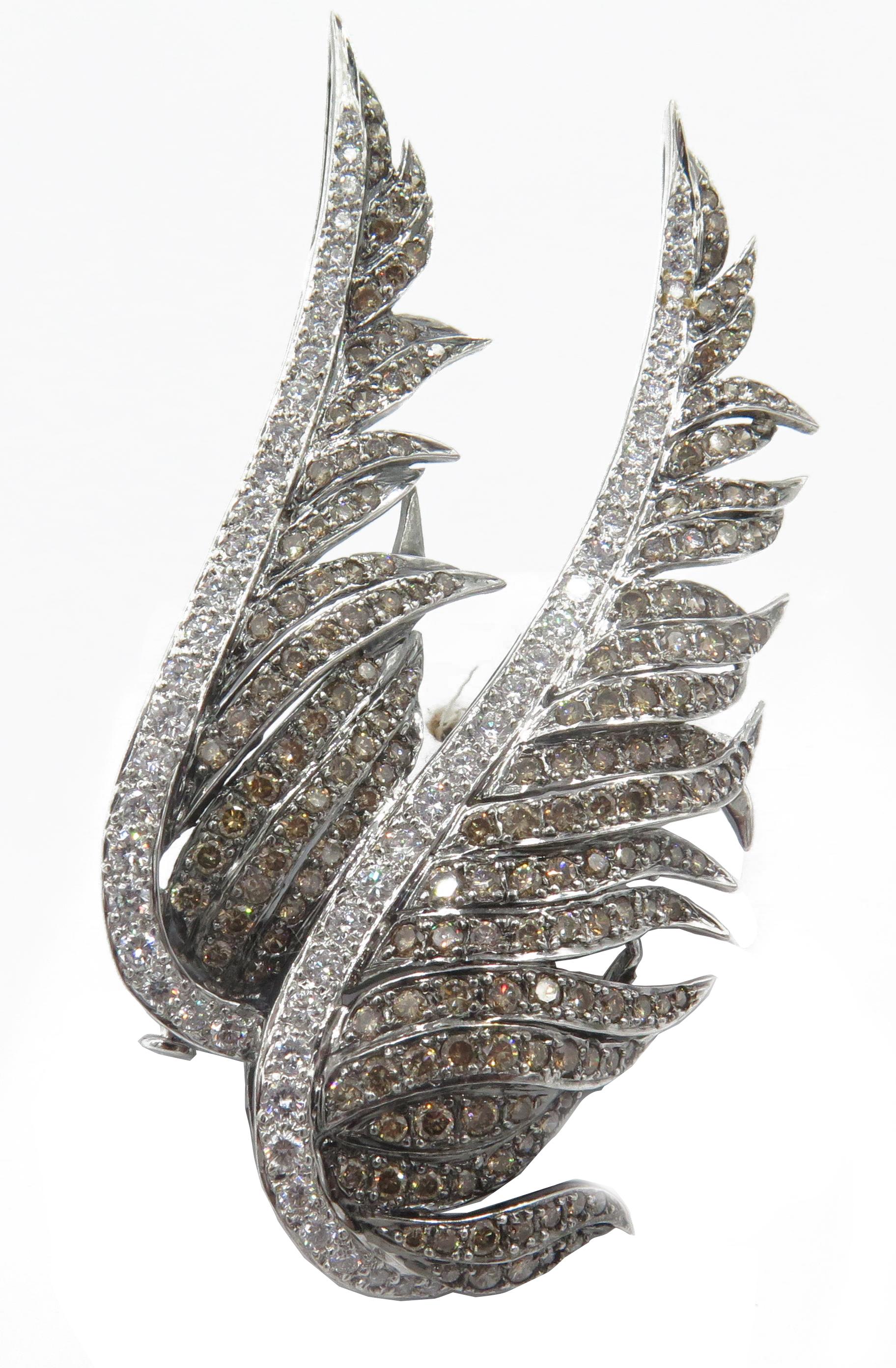 A beautifully crafted pair of 18k white gold wings encrusted with diamonds are the  focus of this exquisite brooch. A row of round white brilliant diamonds outline the front of each wing, creating the graceful curves. The detailed feathery part of