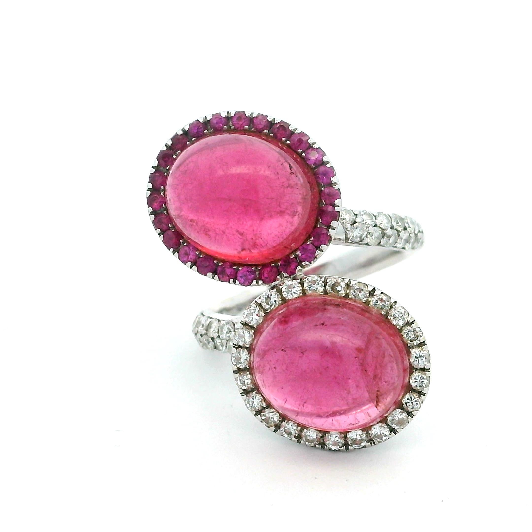 Un anello da cocktail contemporaneo di grande effetto, progettato con un'elegante forma a bypass e realizzato in oro bianco 18 carati. L'anello presenta due vibranti cabochon di tormalina rosa, del peso complessivo di circa 10,00 carati, la cui