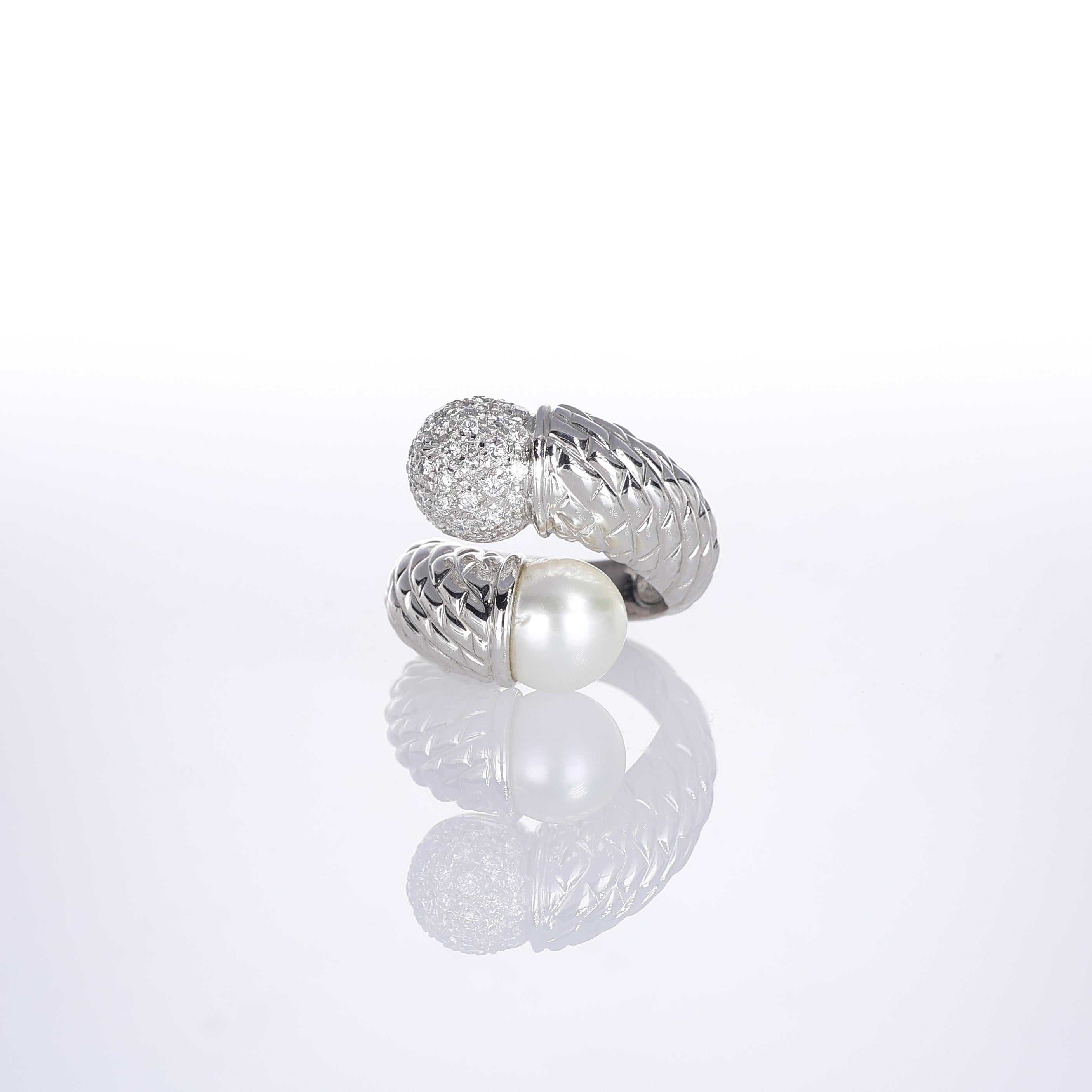 A refined 18k white gold bypass ring featuring a lustrous pearl on one end and a diamond-pavé sphere on the other. The intricate goldwork enhances the contrast between the smooth, organic pearl and the brilliance of the diamonds, creating a