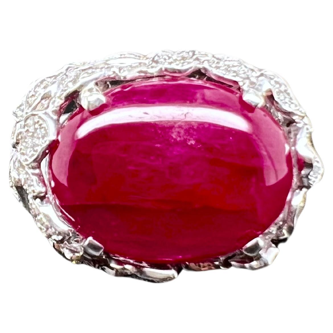 This remarkable ruby cabochon is set in a custom made 18k white gold diamond setting. The cabochon ruby is set east west style and has an amazing red-pink hue glow. The diamond setting has a flower pattern that elevate and hold up the ruby. The ring