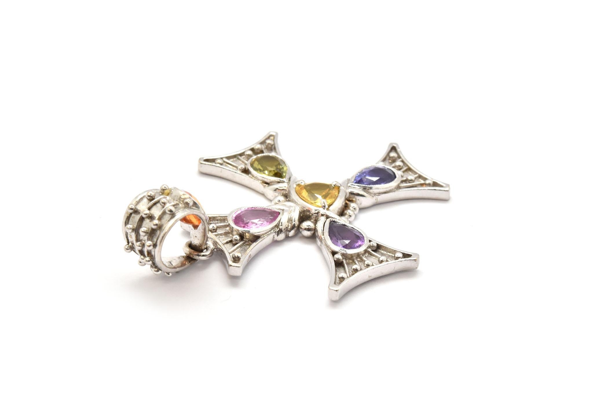 This colorful cross features rainbow colored sapphires set into 18k white gold. The sapphires are orange, pink, yellow, green, purple and blue for a total weight of approximately 6 carats. The cross measures 50x35mm, weighs 14.55 grams.