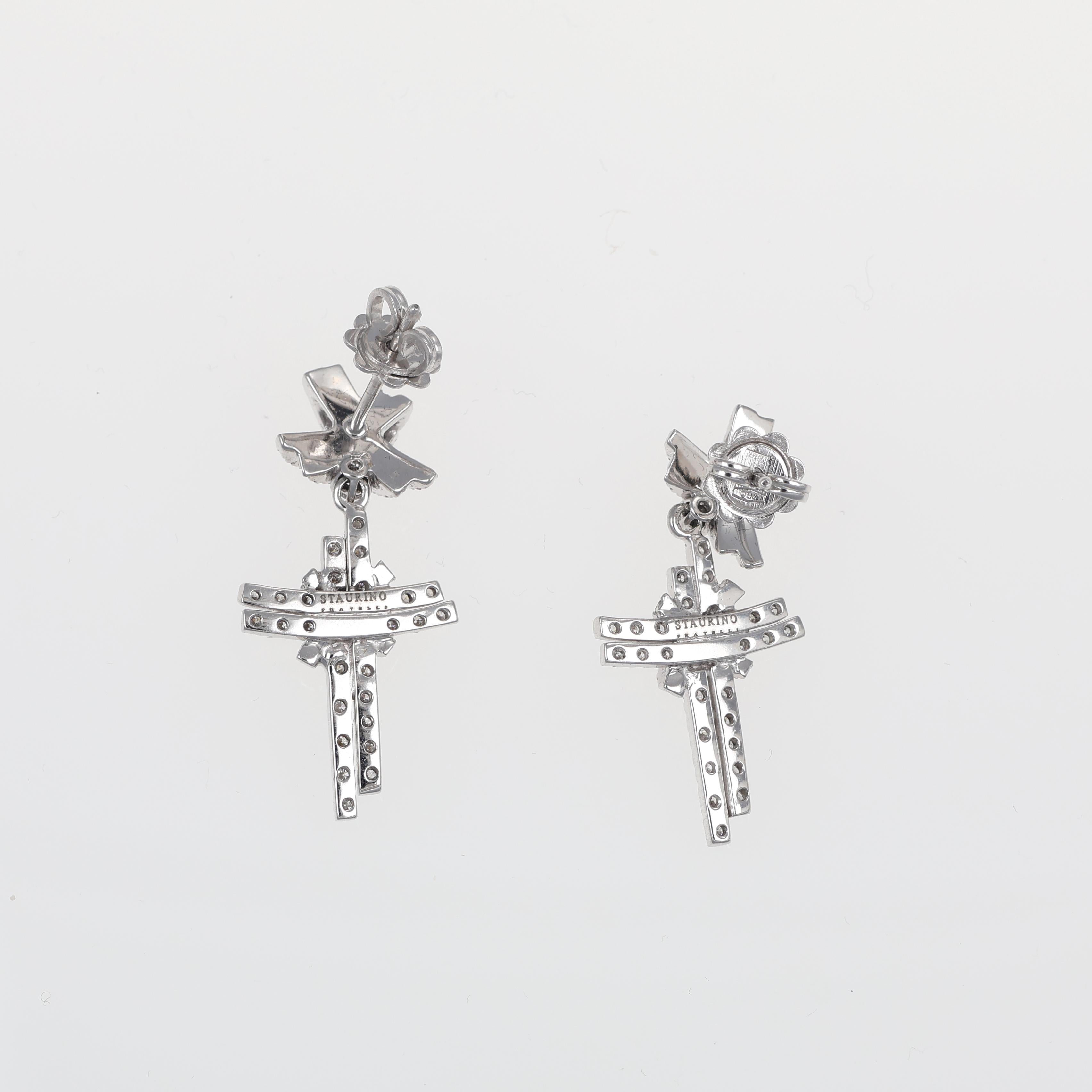 A refined pair of 18K white gold drop earrings featuring a striking cross motif adorned with natural brilliant-cut diamonds. The delicate yet bold design incorporates intricate detailing, making these earrings a sophisticated statement piece. The