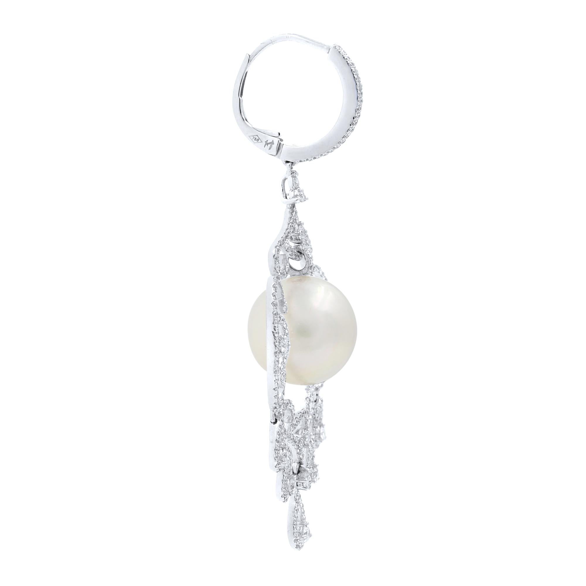 These divine white gold bridal pearl flower earrings dazzle with pave round cut diamonds in a flower motif. A 12mm pearl dangles just in the center a feminine floral motif drop earrings for women, letting you shine everywhere you go. These stunning