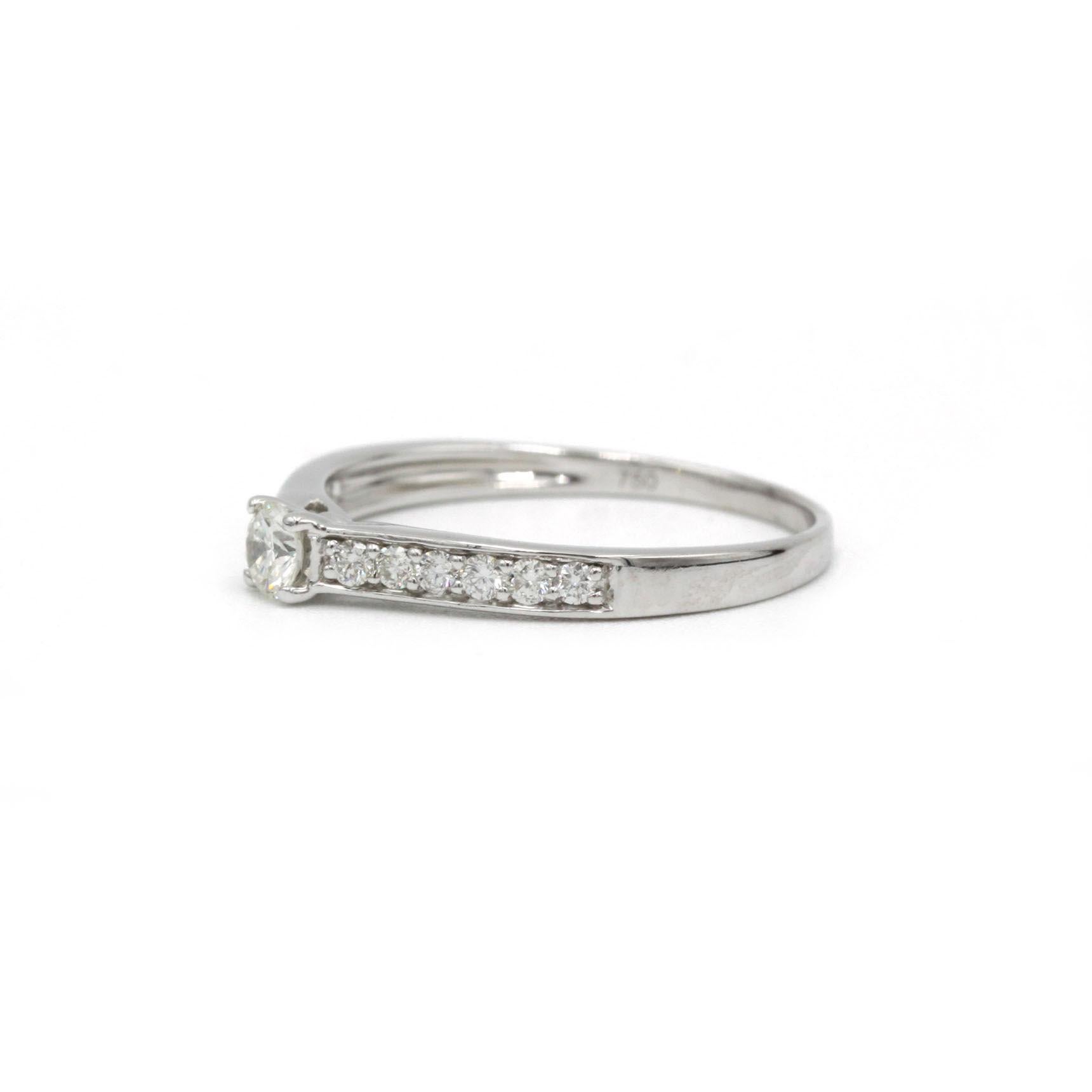 Dieser diamantbesetzte Solitärring aus strahlendem 18-karätigem Weißgold zeichnet sich durch schlichte, moderne Eleganz aus. Ein Diamant im Brillantschliff, Farbe G, VS-Klarheit (0,18 ct) ist in einem klassischen Vierzackenkopf eingebettet, während