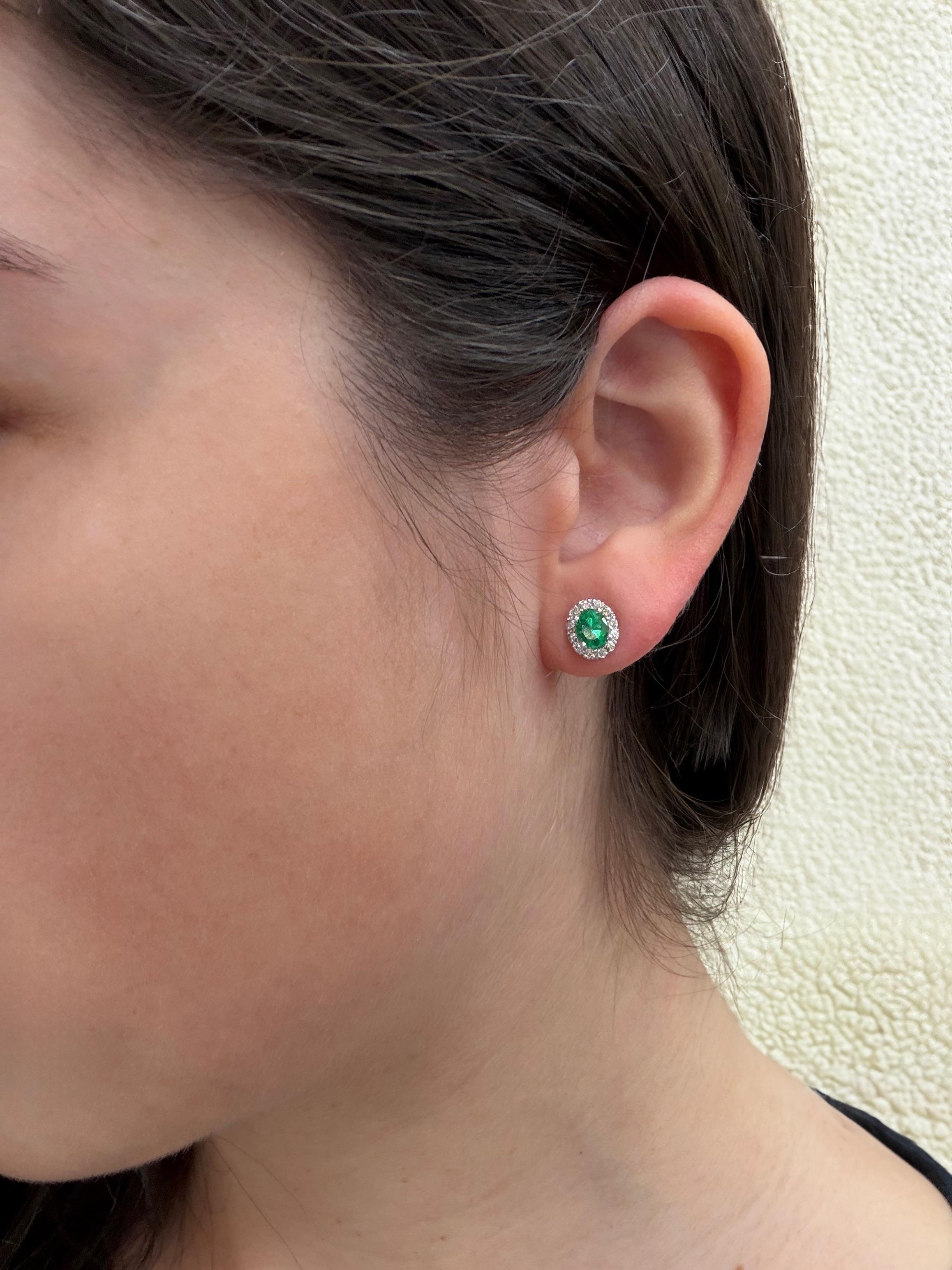 La boucle d'oreille parfaite pour tous les jours, des émeraudes ovales vibrantes entourées d'un halo étincelant de diamants. Fabriqués en or blanc 18 carats, ces clous d'oreilles ajoutent la bonne touche de couleur et d'élégance en toute
