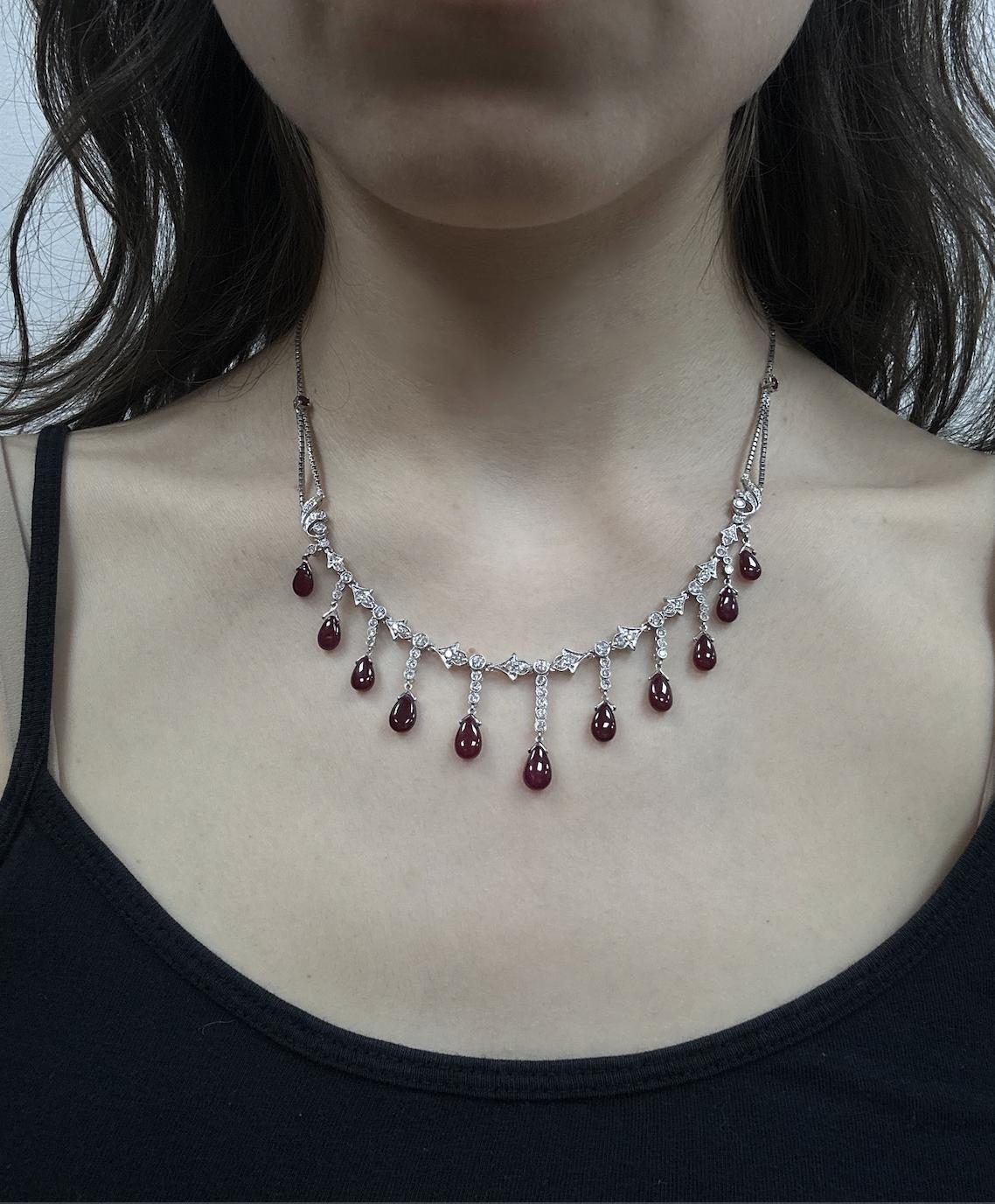 Elegante e ricca di dettagli, questa collana in oro bianco 18 carati presenta 11 lussuosi rubini cabochon per un totale di 17,01 carati, abbinati a 1,90 carati di diamanti scintillanti. I rubini sono delicatamente sospesi da una catena ornata di