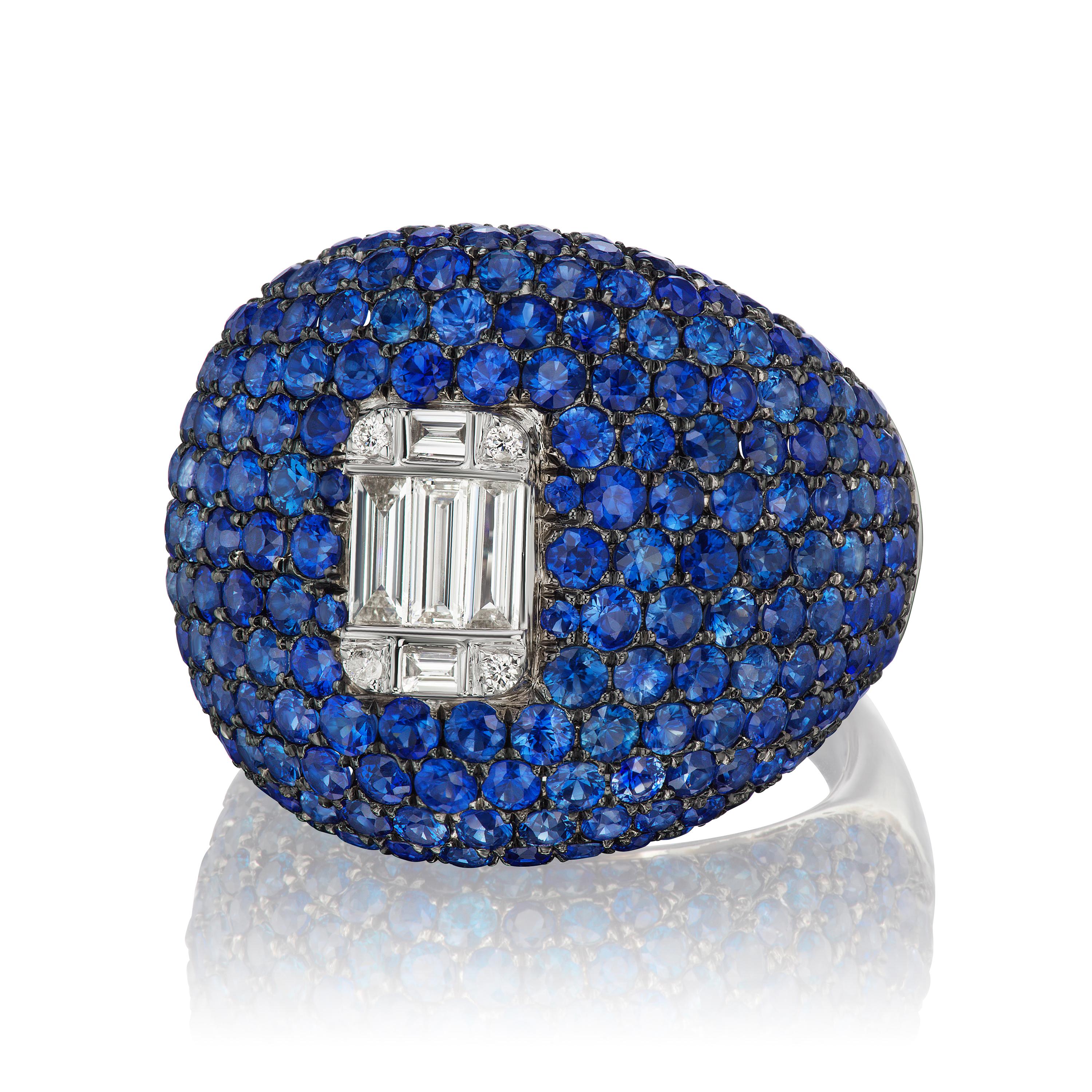 A statement making dome ring crafted in 18 Karat white gold. This dome ring is featured with 4 round diamond, 5 baguette diamond and 226 pave blue sapphires. The stock size of the ring is US 7. The ring can be resized with a delivery time of 3