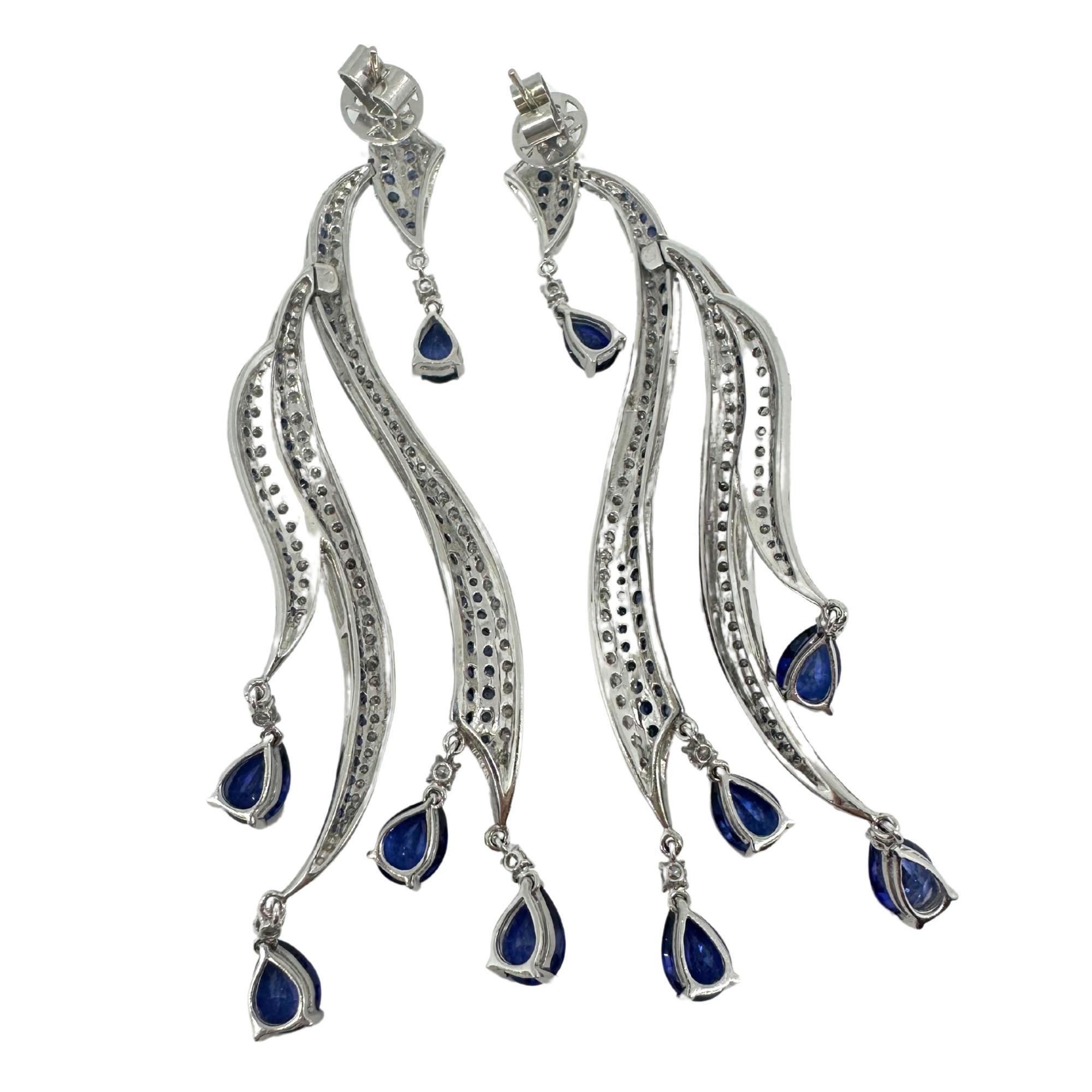 Ces boucles d'oreilles en or blanc 18 carats, composées de diamants et de saphirs, imitent avec grâce le mouvement des vagues de l'océan, avec des diamants scintillants et des saphirs d'un bleu profond qui tombent en cascade dans un design élégant