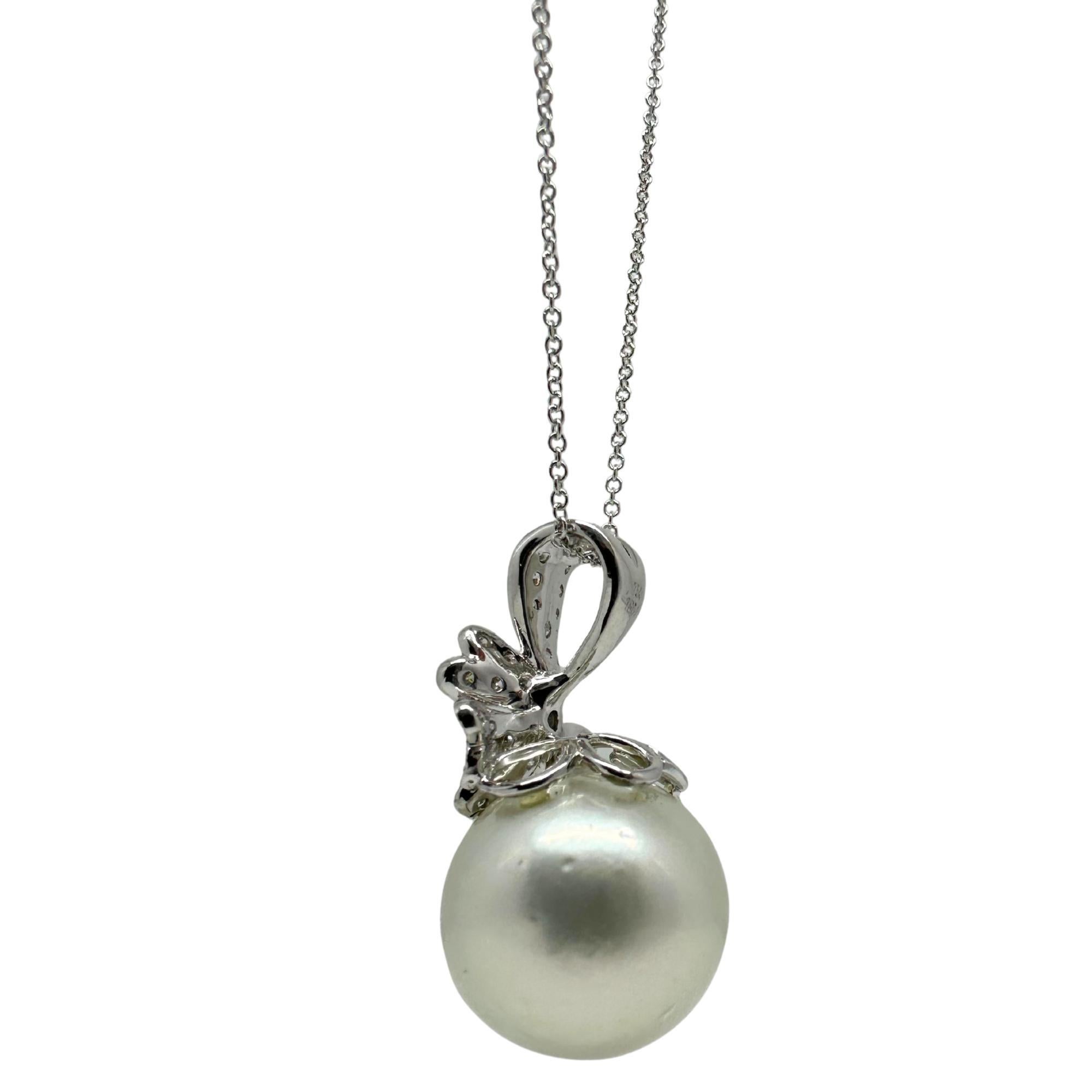 Elegante y femenino, este impresionante collar colgante de perlas está elaborado en oro blanco de 18 quilates y adornado con brillantes diamantes. Un elegante motivo floral se asienta sobre una luminosa gota de perla blanca, haciendo de esta pieza