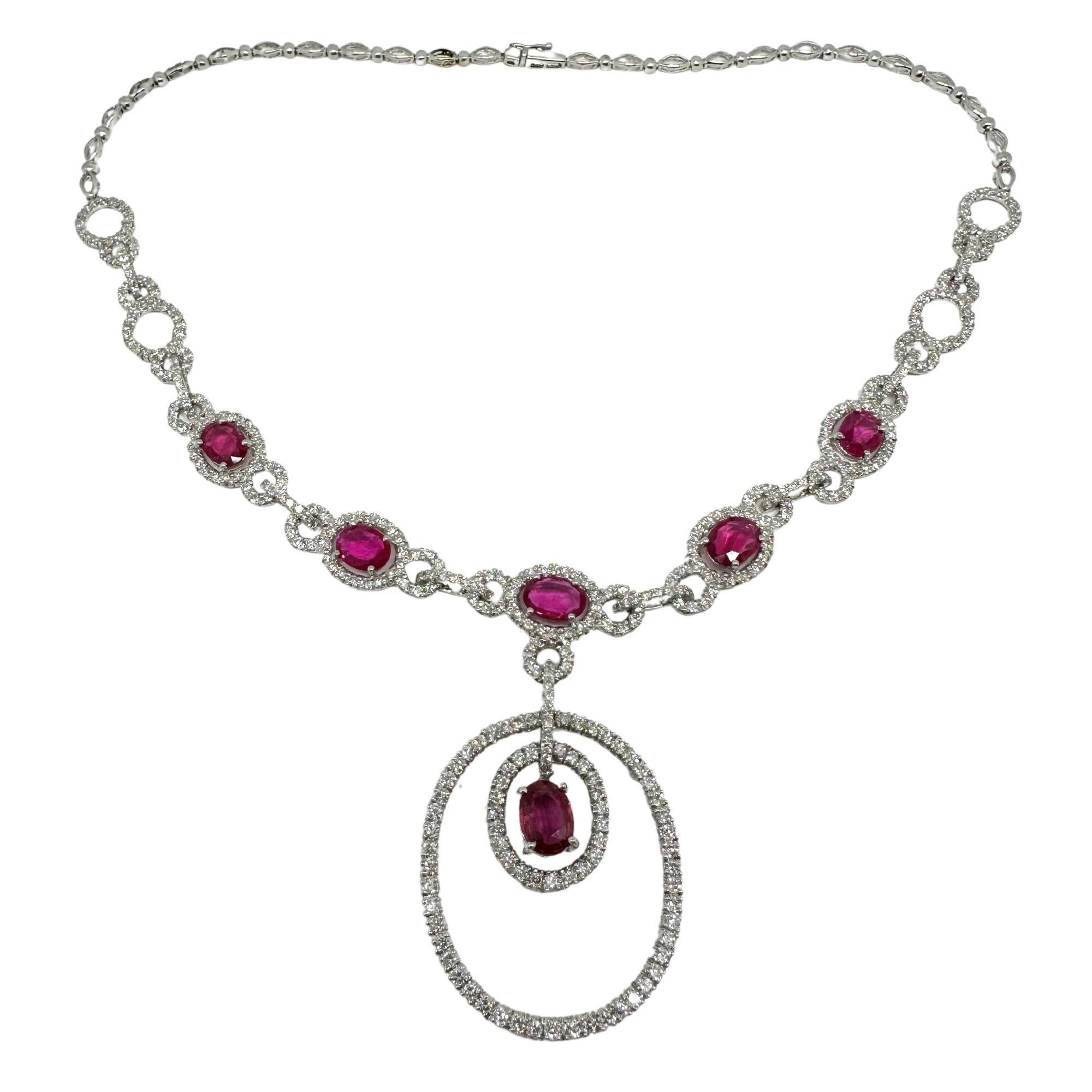 18K White Gold Ruby and Diamond Drop Necklace. 30.4 grams, 16 inches long with a 1.75-inch drop. Set with 6.74 carats of diamonds and 6.83 carats of vivid rubies in a scrolling oval design, centered by a dramatic double-drop pendant. Marked 