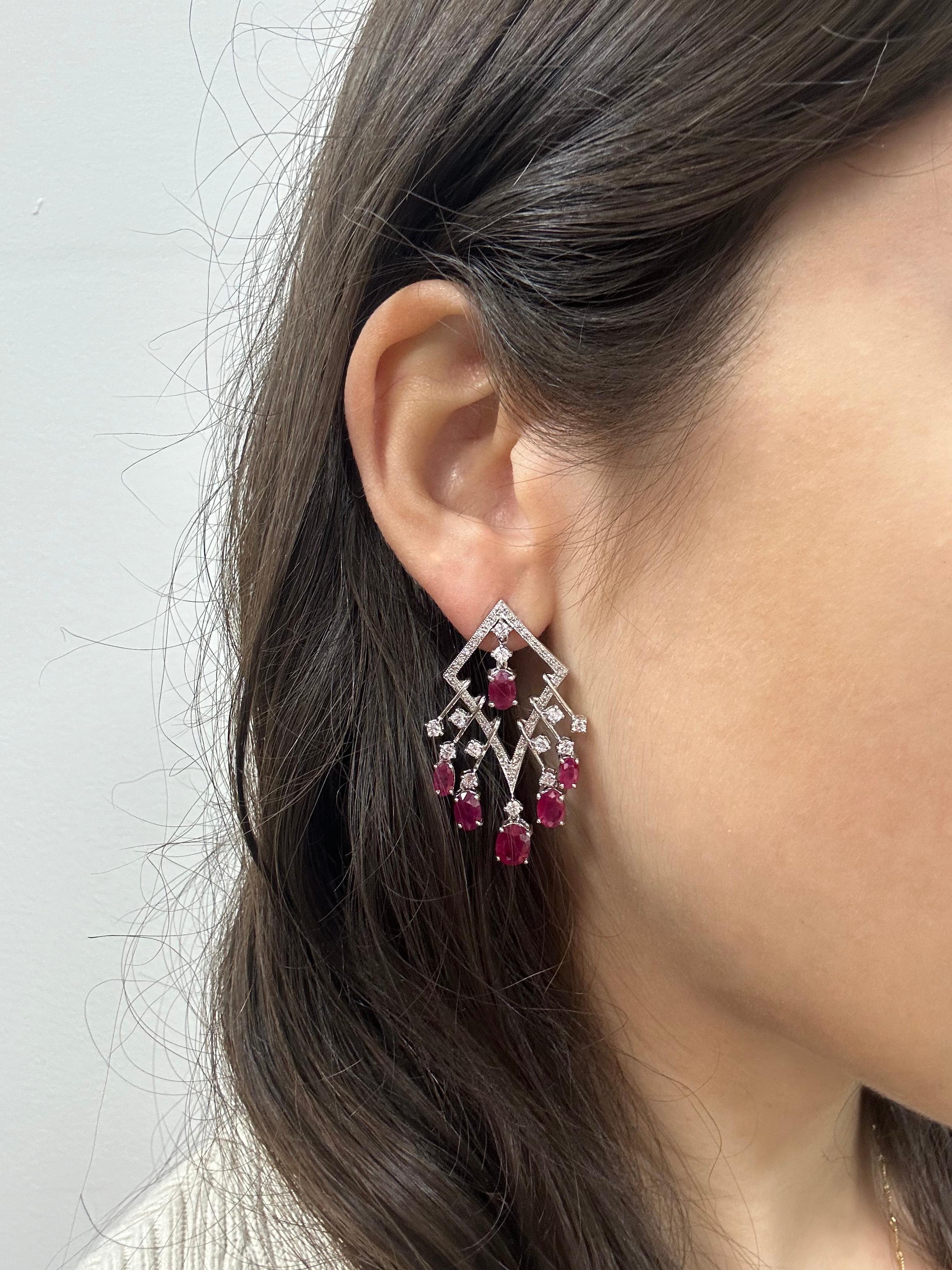 Elegant 18K white gold earrings featuring a total of 7.20 carats of vivid rubies and 1.40 carats of sparkling diamonds. Each earring is set with six richly colored rubies, framed by brilliant diamond accents. Measuring 1.50 inches long and 0.75