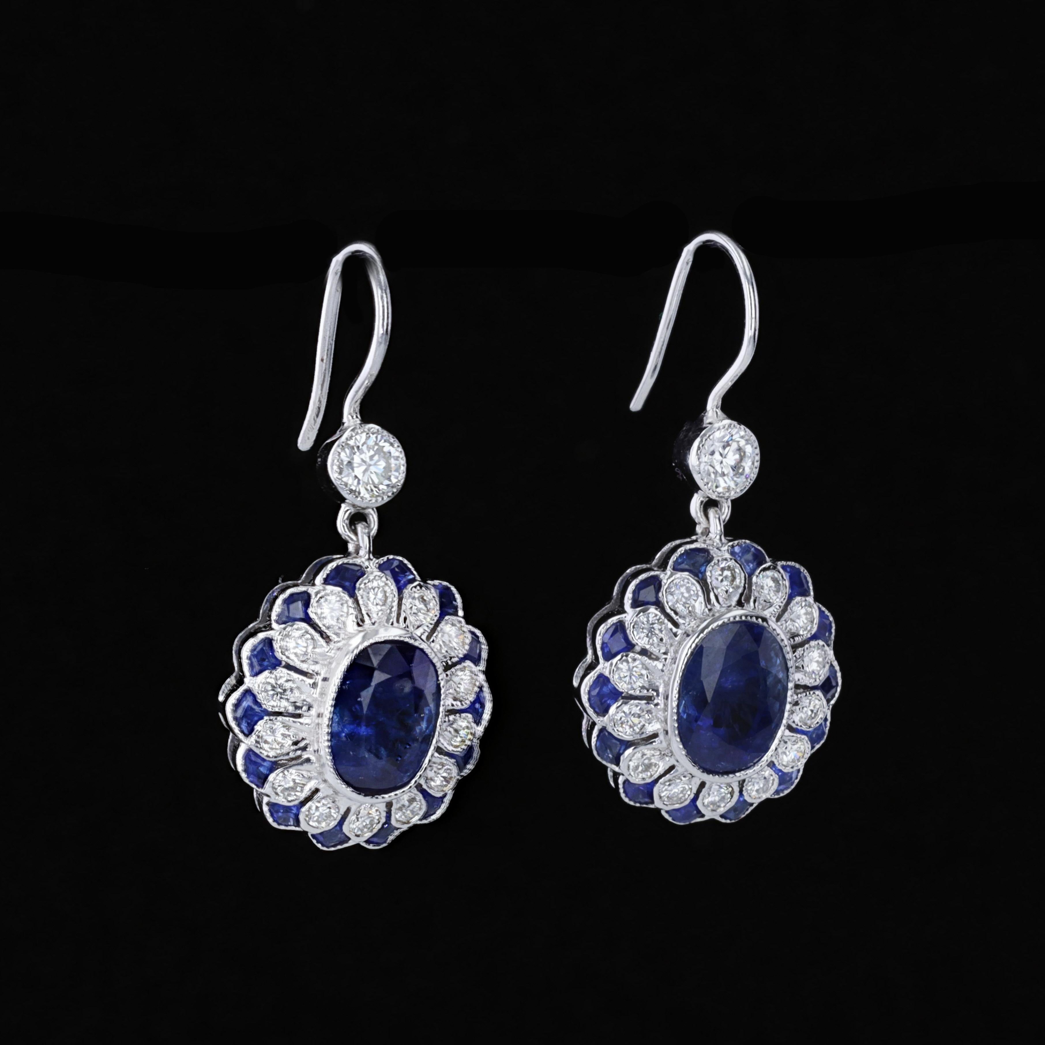 These sparkling earrings feature lovely oval cut sapphires that weigh approximately 3.71ct. The sapphires are accentuated by sparkling round cut diamonds and fan shape sapphires that weigh approximately 0.92ct and 0.72ct respectively. The color of