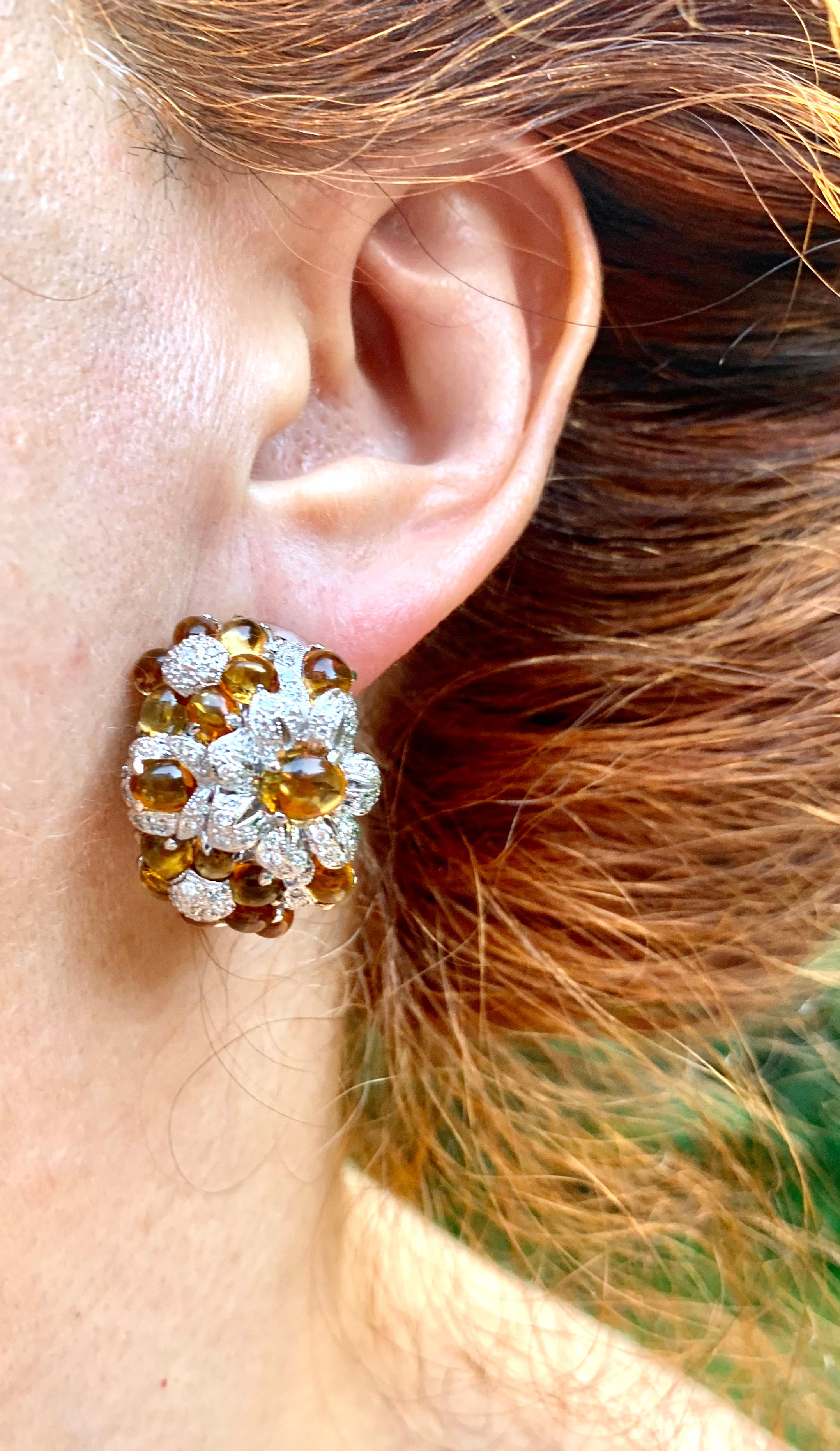 Beautiful estate 18K white gold, diamond and cabochon golden topaz earrings, each composed of seven flower clusters, alternating design of flowers with diamond centers and topaz petals and with topaz centers and diamond petals.
Fine golden cabochon