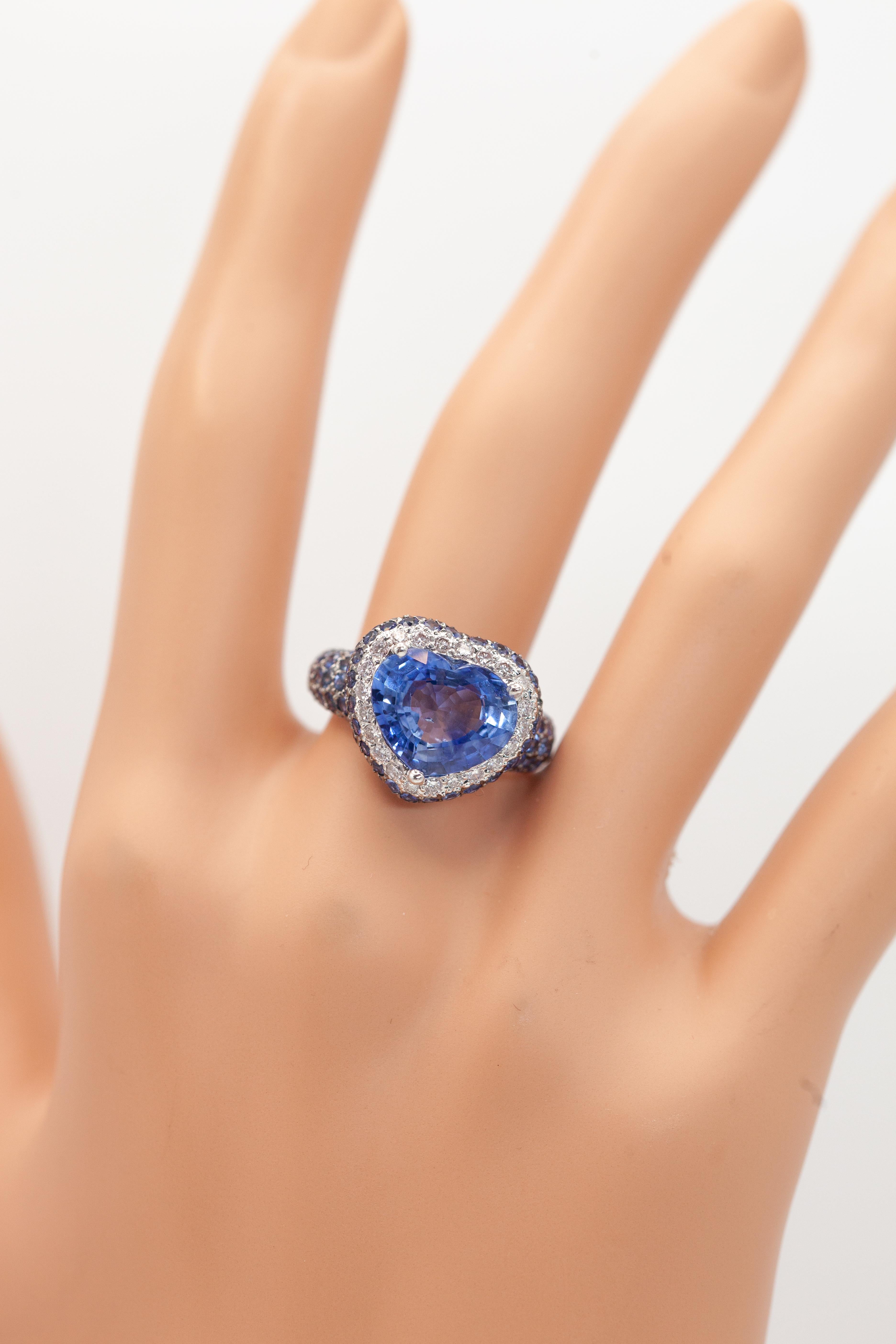 Dieser Diamant-Saphir-Ring aus 18 Karat Weißgold mit einem herzförmigen Saphir in der Mitte, umgeben von einem Halo aus 22 runden Diamanten mit der ungefähren Farbe G und der Reinheit VS-SI, ist mit runden Saphiren in Pave-Fassung geschmückt, die