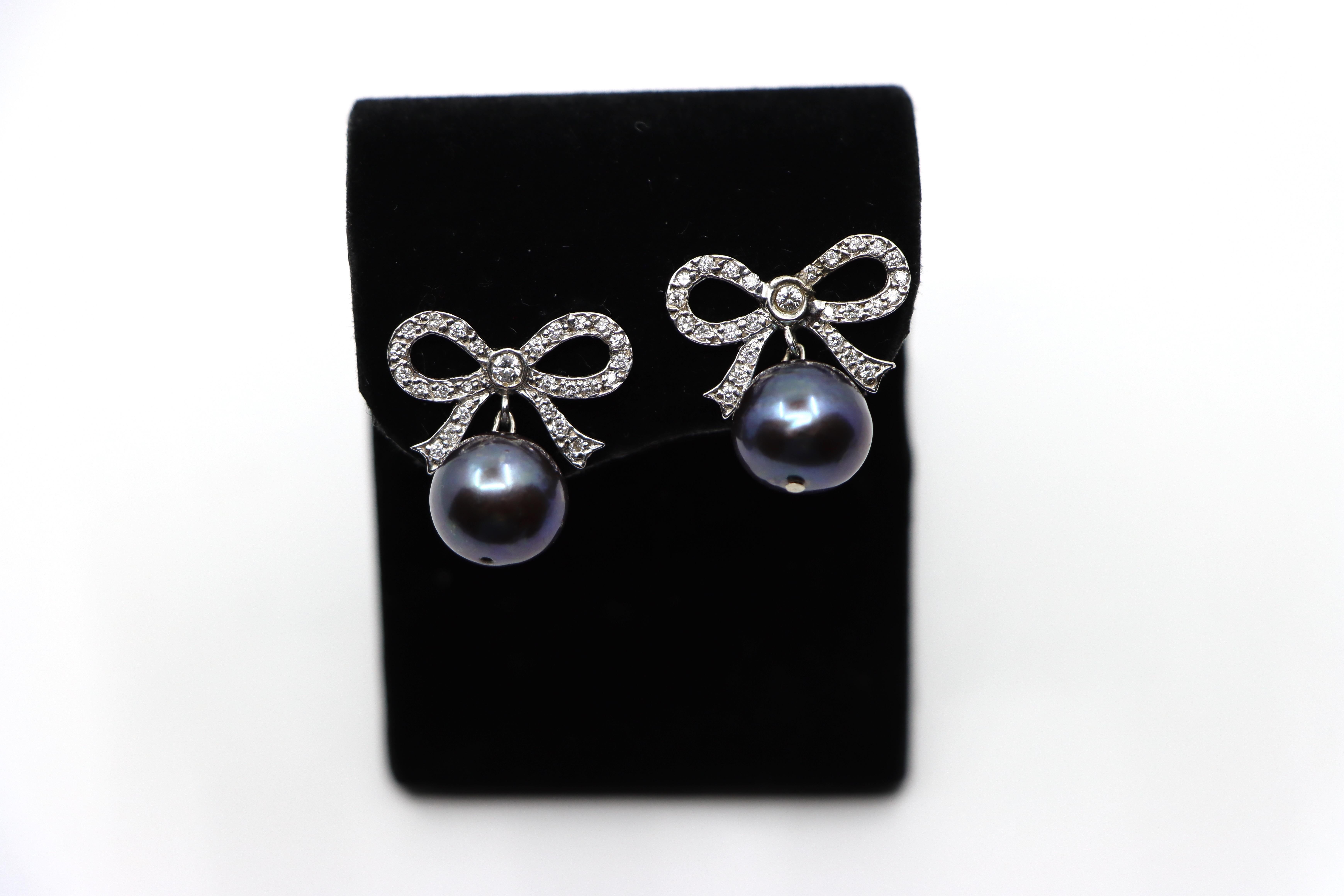 18K White Gold Diamond Bow Tie Black Pearl Earrings
With 14K White Gold Clasp

Approximate Dimensions:
2 cm (Length)  
2 cm (Width)
10.92 mm - 11.03 mm  (Pearl) 
Approx. 0.62 carat (Diamonds) 
8.1 grams in weight.