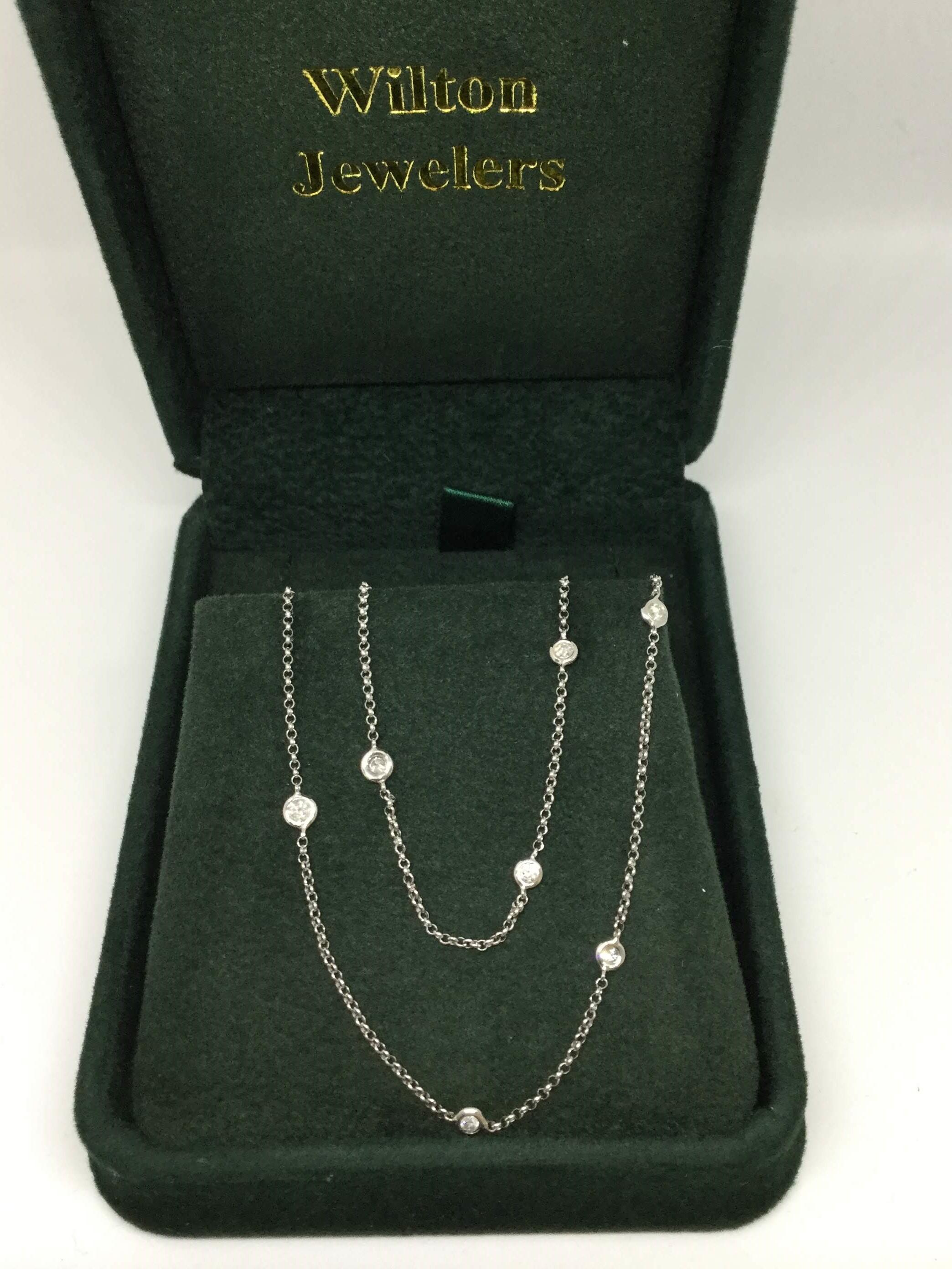 18K White gold diamond by the yard style necklace. The necklace contains 12 round brilliant cut diamonds that are bezel set. The necklace is 16 inches with a 2 inch extension.