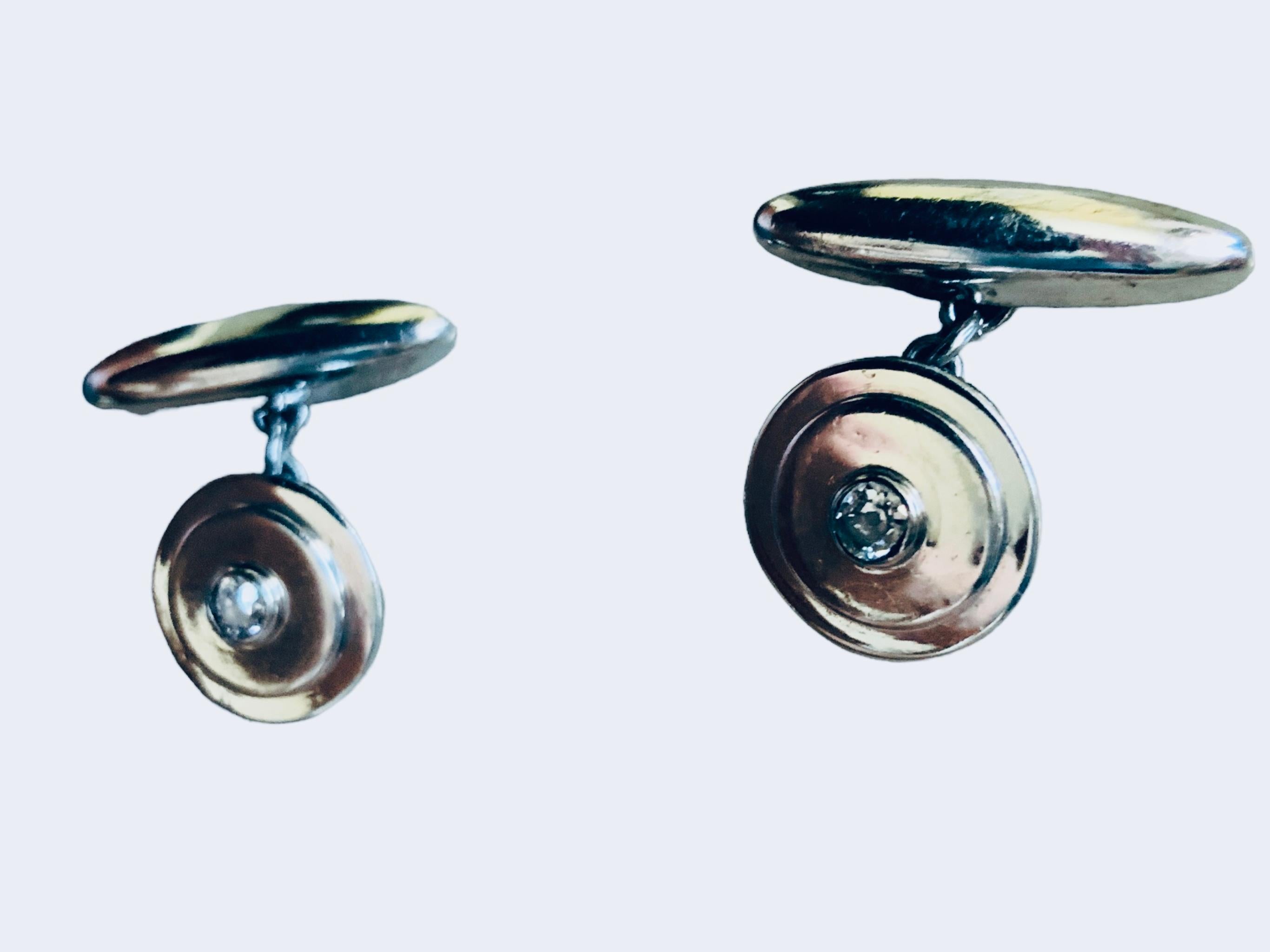 This is a 18K white gold chain link pair of cufflinks. It depicts a disc shaped cufflinks decorated in the center with some pave round diamonds 