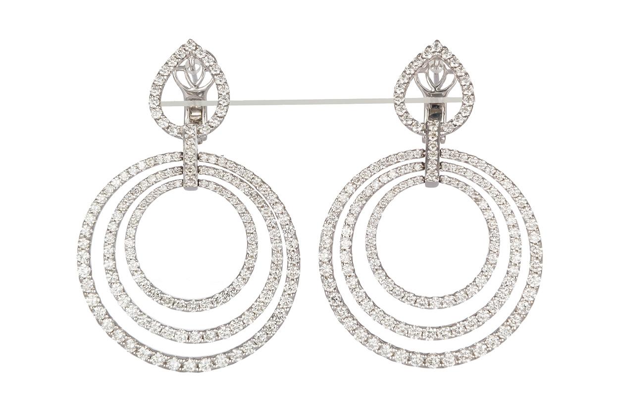 We are pleased to present these 18K White Gold & Diamond Concentric Circle Dangle Earrings. These beautiful earrings feature a dangle drop design with an estimated 4.50ctw G-H/VS-SI Round Brilliant Cut Diamonds set in 18k White Gold. The earrings