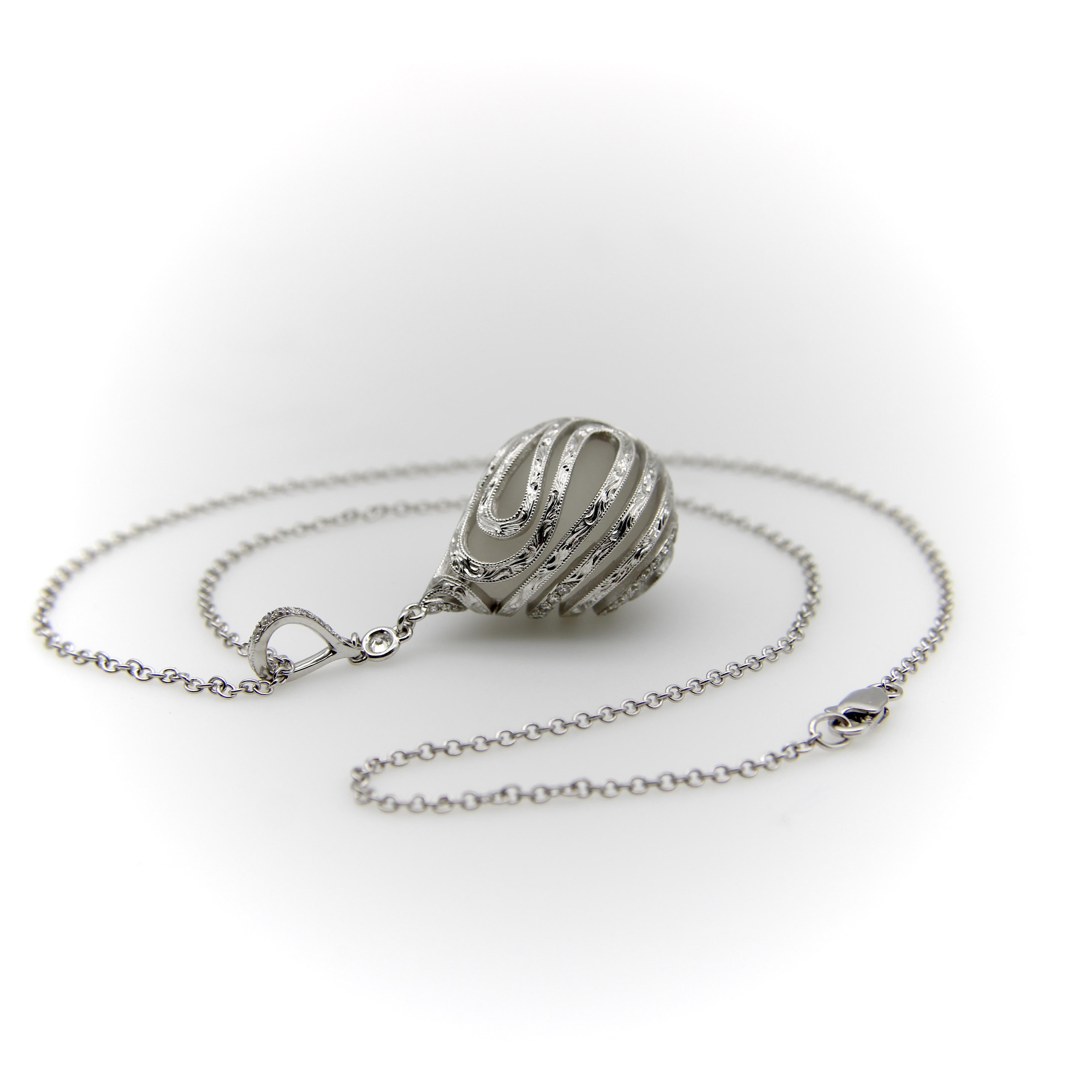 This drop-shaped rock crystal pendant is wrapped in a masterfully hand engraved and diamond encrusted cage setting. The 18k white gold setting swirls around the crystal, mimicking its shape to create a fabulous Art Deco-like piece. The piece is