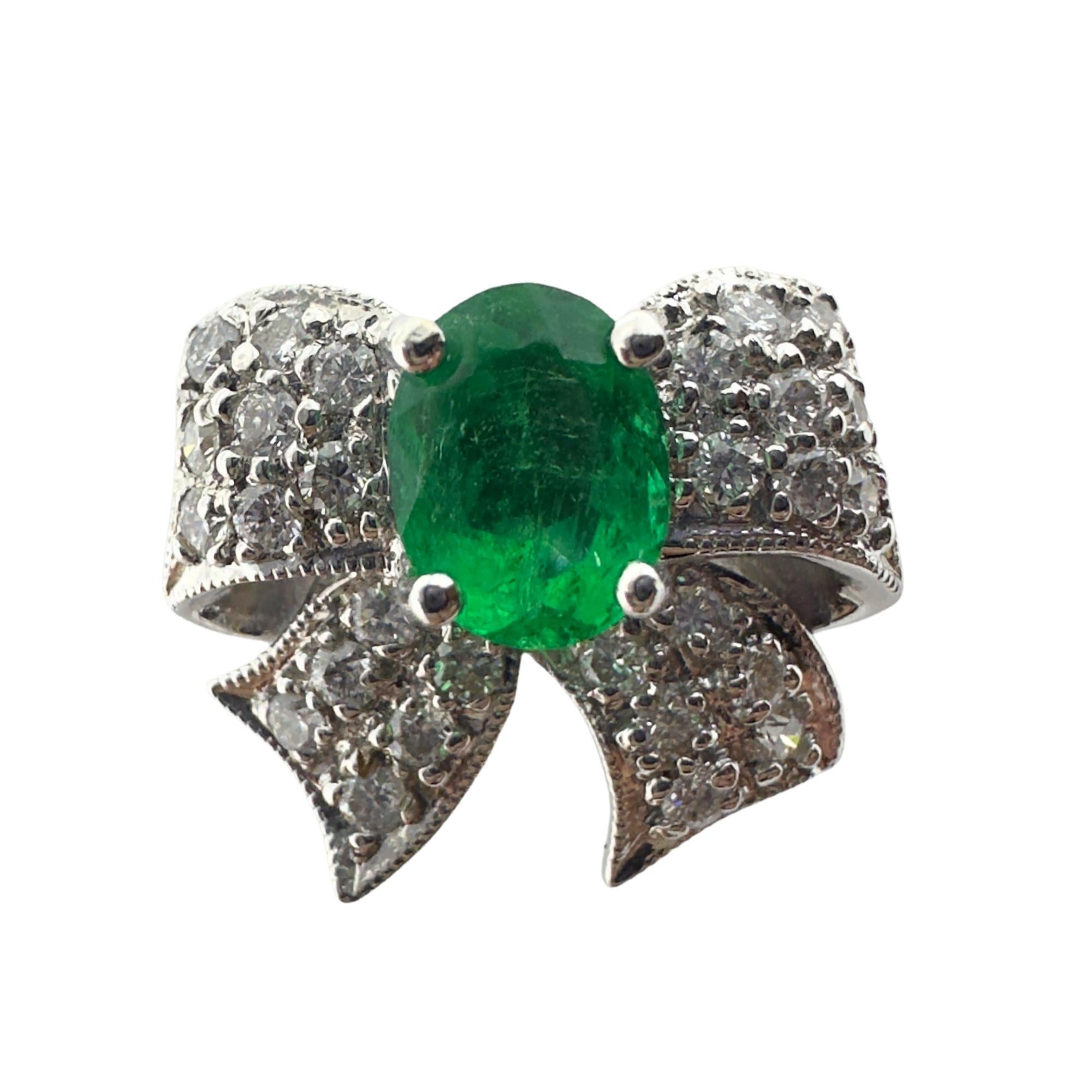 Charmante et élégante, cette adorable bague en or blanc 18 carats est ornée de 0,36 carats de diamants. En son centre, une jolie émeraude de 0,62 carat est posée sur un nœud de diamants. Pesant 5,8 grammes et mesurant 13,02 mm de large, la bague