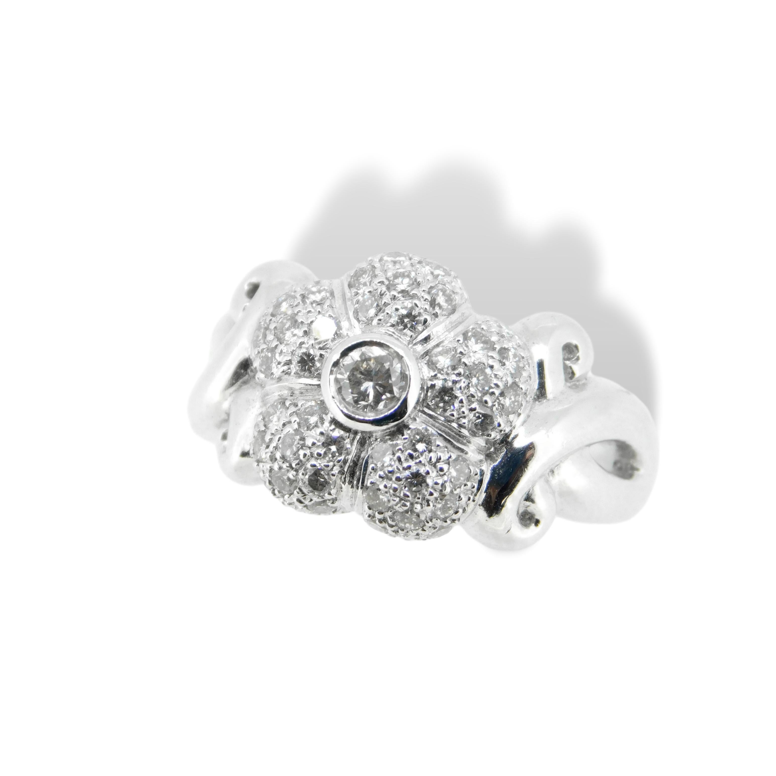 18K white gold flower ring featuring 3/4 carat of round brilliant cut diamonds. The center  4.1mm(approx) diamond is bezel set and surrounded by diamonds which are pave set.     Ring size is 6 3/4, weighs 5.4dwt. and is a high quality contemporary