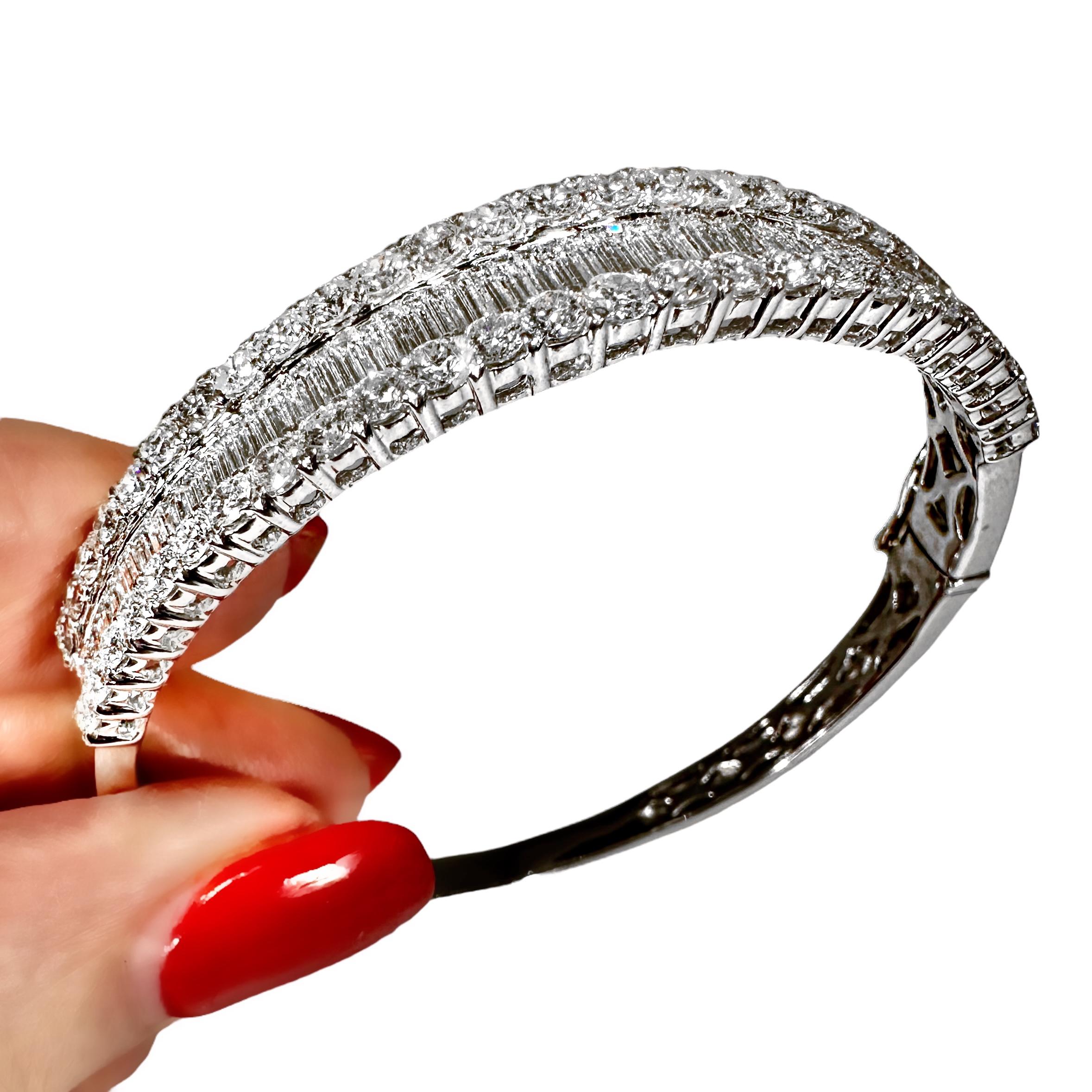 The top half of this stylish 18K white gold and diamond bangle sparkles and scintillates with every movement. It is set with a total of approximately 54 modern round brilliant cut diamonds in two lines flanking a continuous band of approximately 54