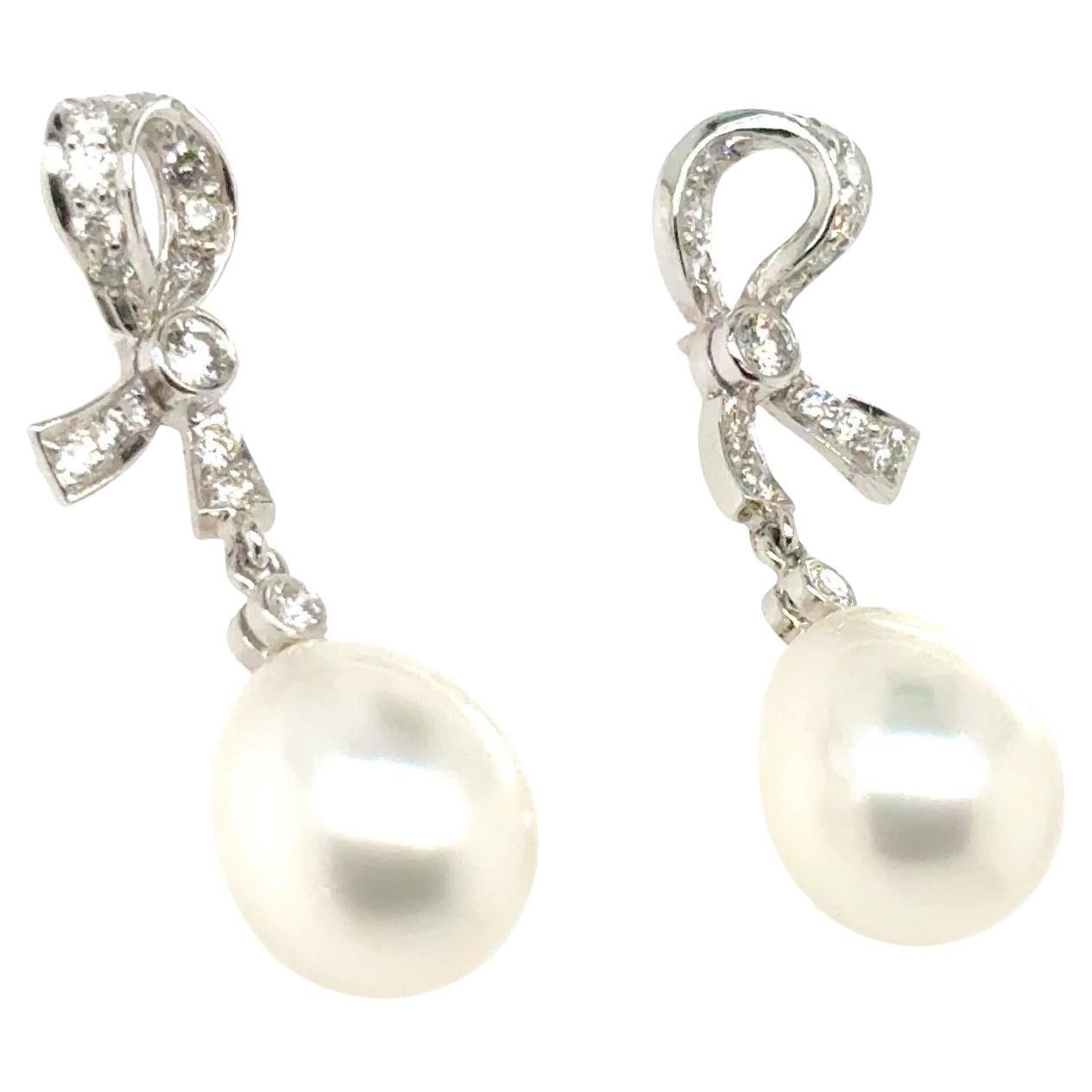 These ribbon-inspired earrings cradle two South Sea pearls that dangle delicately, catching light with every movement. 

All set in 18k white gold.
 
Above them, 0.69 carats of diamonds sparkle like morning dew.

Sourced from the warm waters of the