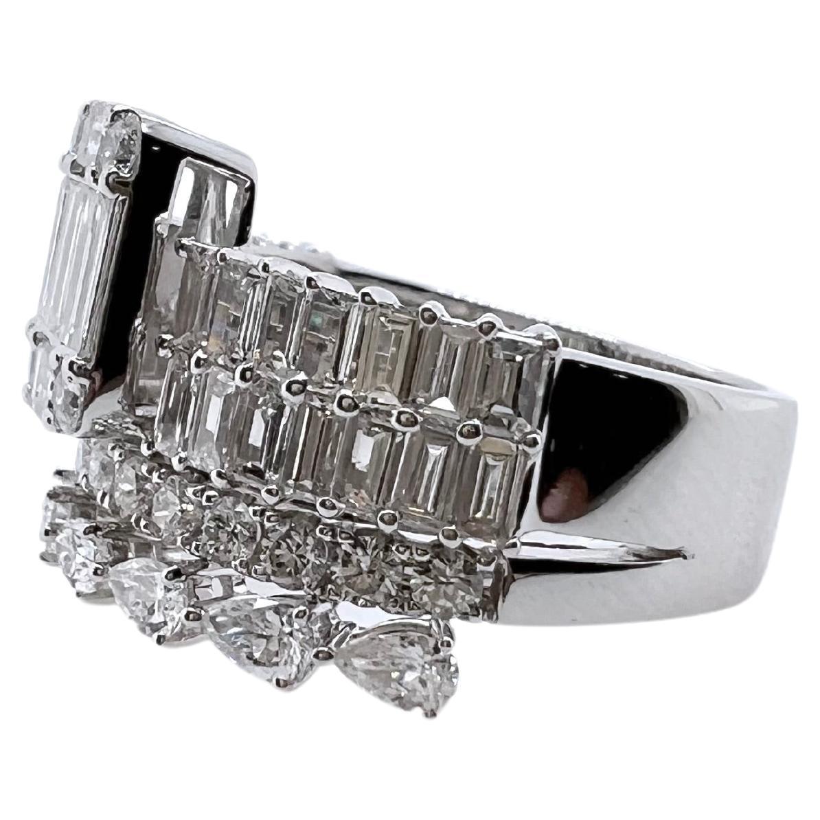 Questo anello è sensazionale! Una visione per gli occhi! Il diamante centrale con incastonatura a illusione è composto da baguette e brillanti rotondi, mentre le fasce sono composte da diamanti a forma di pera, smeraldo e brillanti rotondi. L'anello