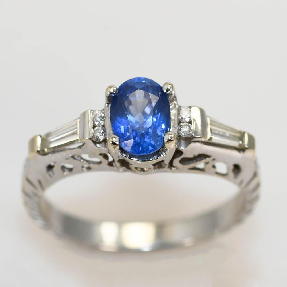 Ladies sapphire and diamond ring in 18k white gold setting.
Stamped 18k and weighs 3.8 grams gross weight.
The natural blue sapphire is an oval shape, 1.12 carats, very fine color and excellent clarity.
The side diamonds are baguette cuts and round