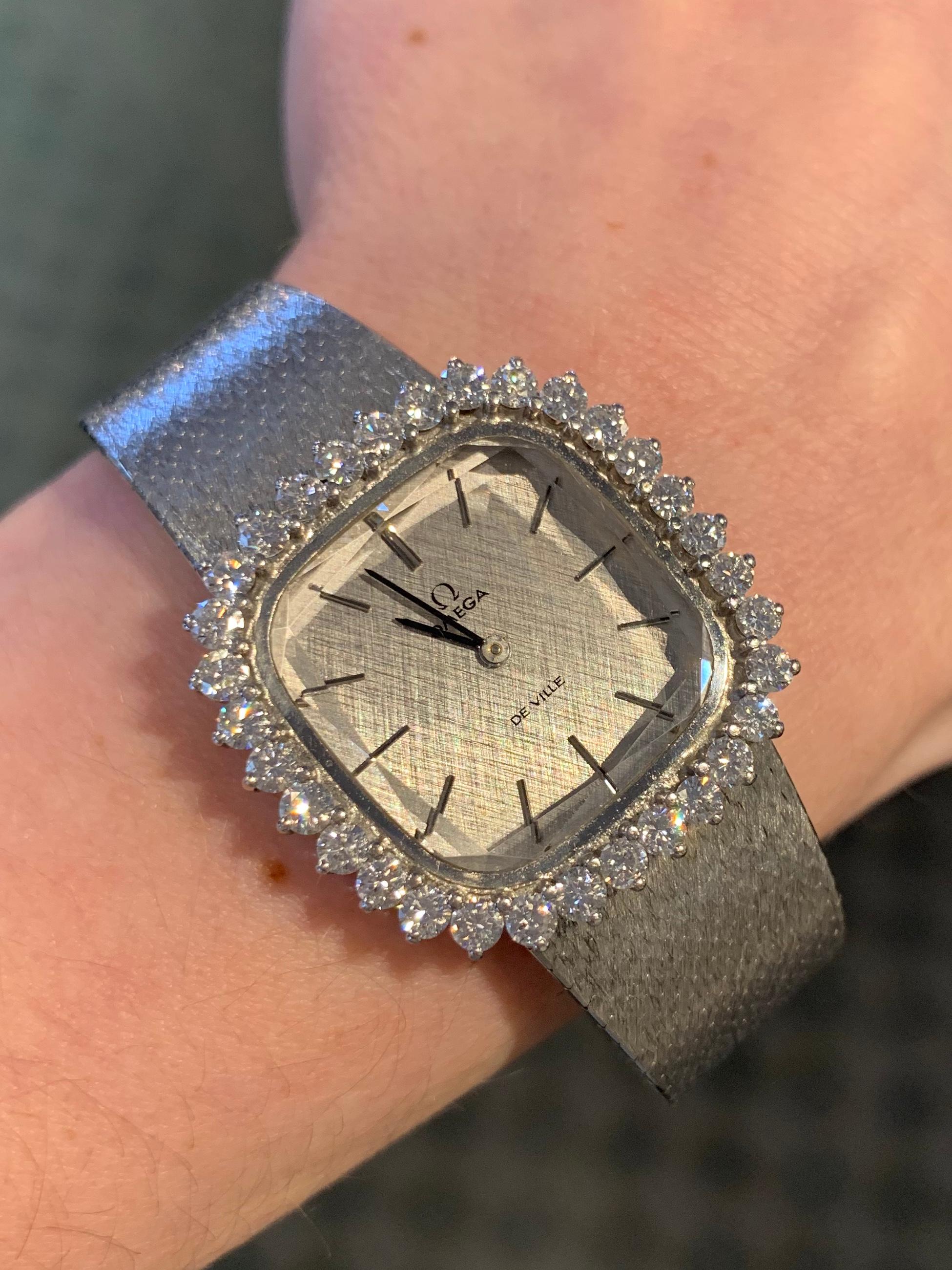 An elegant 18k white gold diamond adorned vintage Omega De Ville mechanical watch with a beautifully carved sapphire crystal. Watch dial is decorated with a beautiful etched silver Florentine finish and features polished stick hour marks. The 28mm