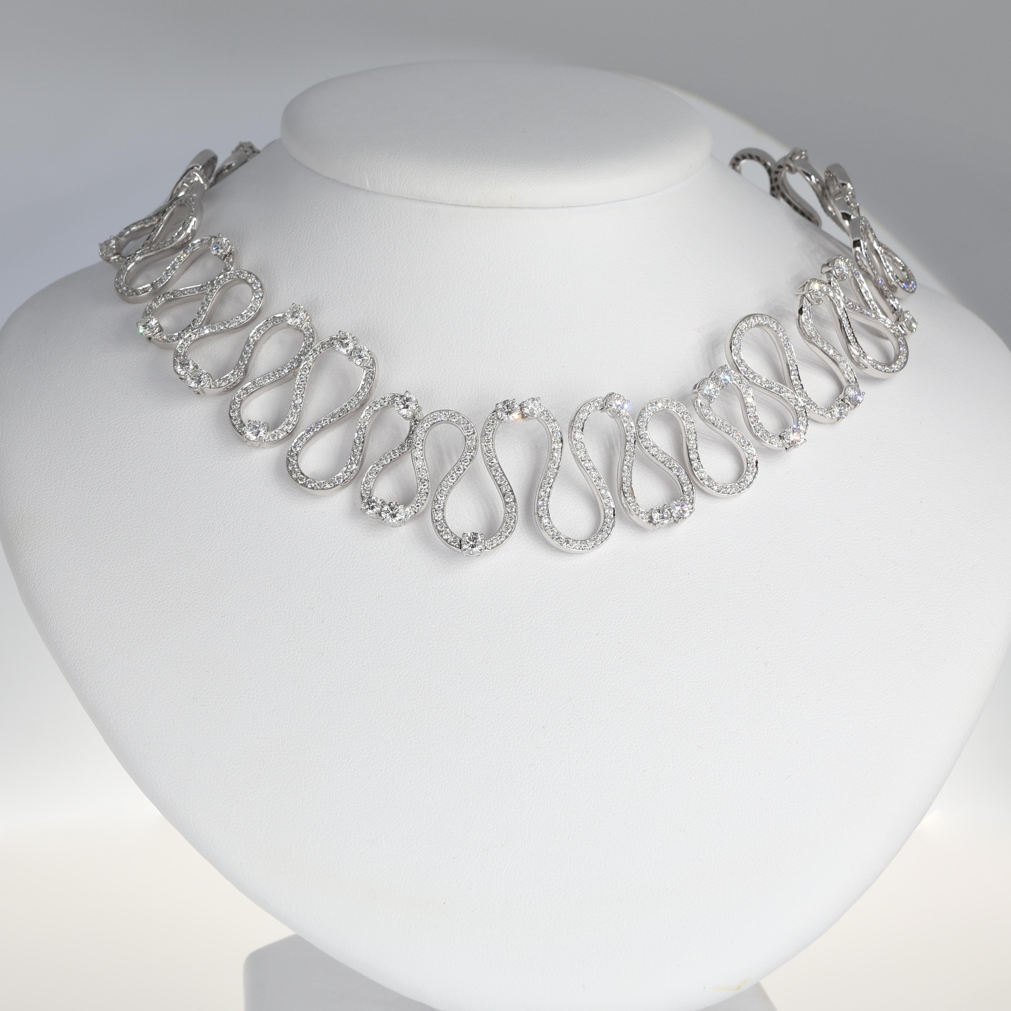 A refined and sculptural choker necklace, crafted in 18K white gold and designed with an undulating wave motif. This rigid collar is adorned with 15.64 carats of natural brilliant-cut white diamonds, creating a fluid yet structured composition that