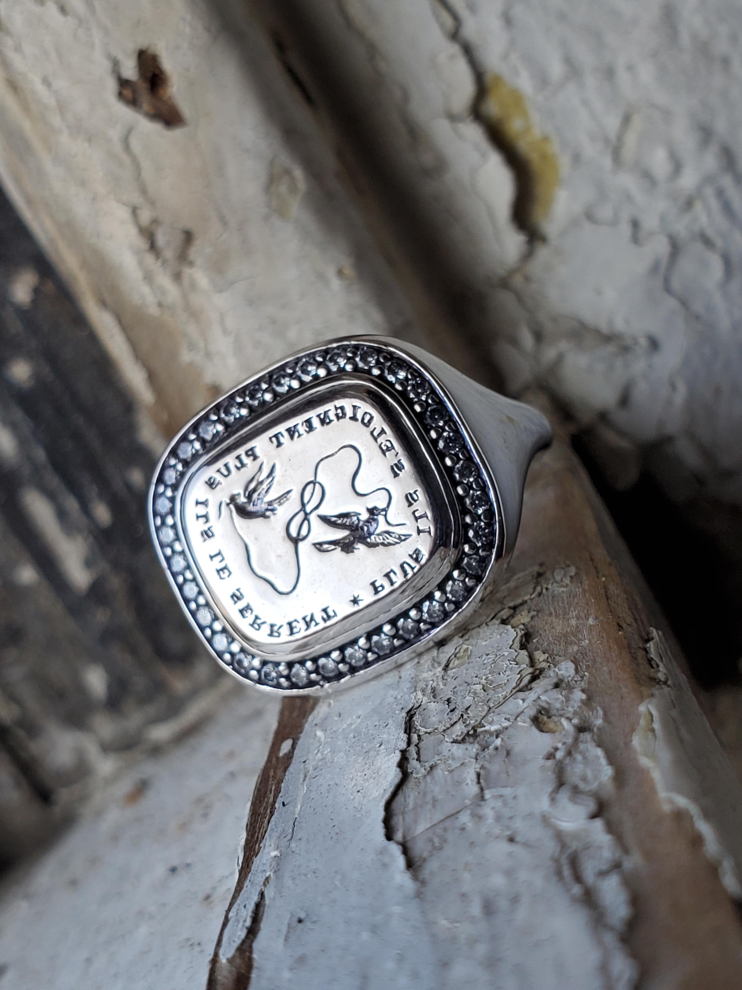 Il nostro anello in oro bianco 18 carati �è caratterizzato da diamanti da .32cttw e da un disegno di sigillo intaglio a mano, che celebra il legame tra due persone. Il motto francese 