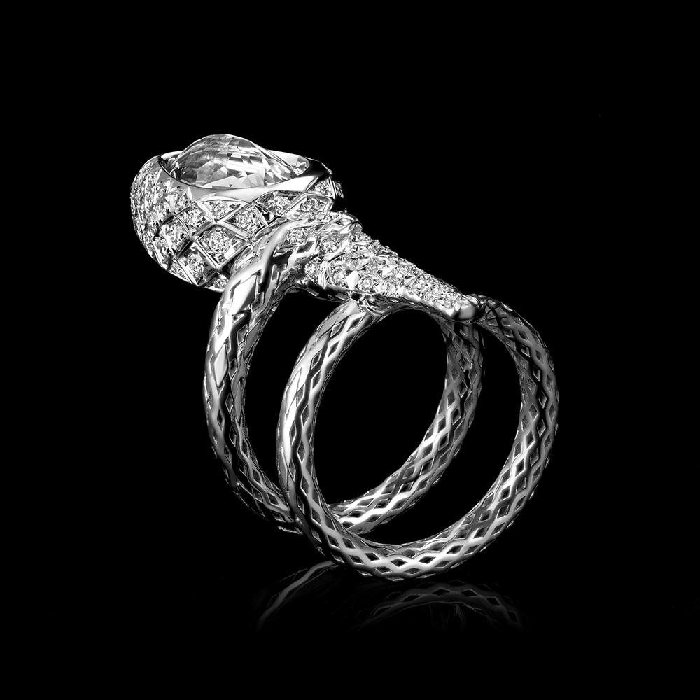 Modern, designer cocktail ring in 18K white gold set with diamonds with intricate details. A serpent coils around the wearer's finger, stretching towards the light of the torch depicted by a large pear shaped diamond and surrounded by a pave of