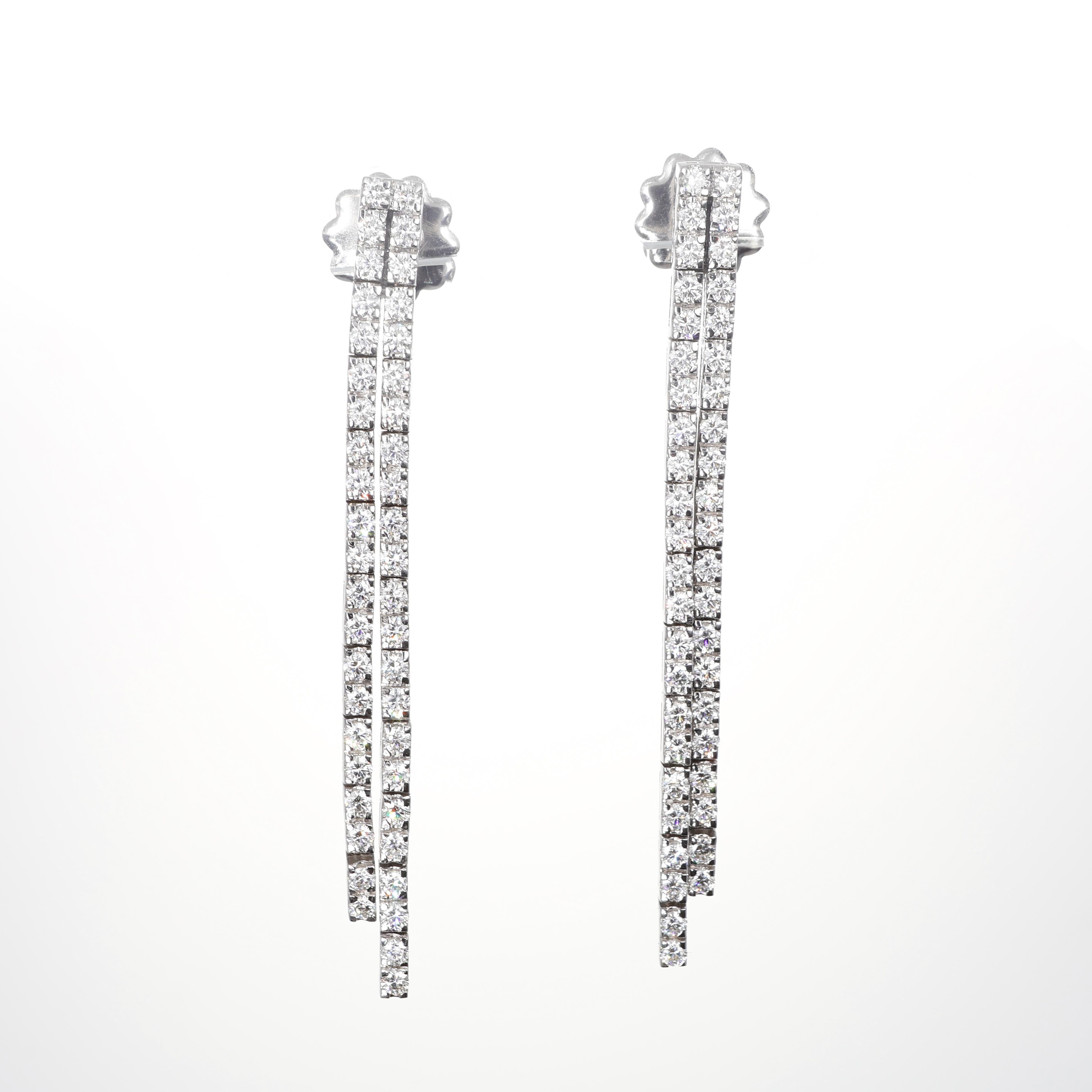 Elegant and luminous, these 18K white gold earrings feature two parallel strands of brilliant-cut natural diamonds, creating a fluid and sophisticated movement. Their sleek, linear design offers a modern touch while enhancing the brilliance of the