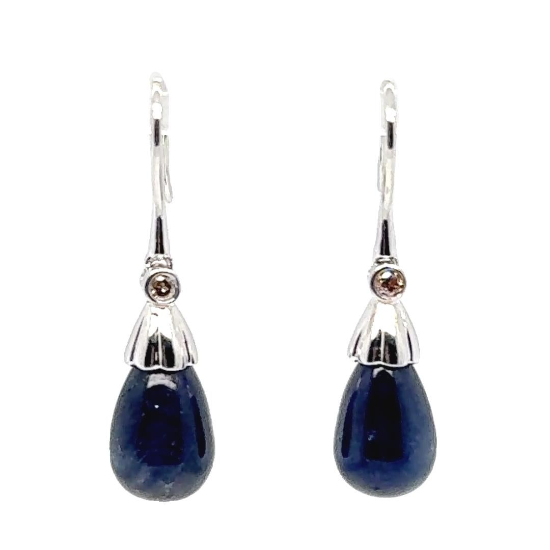 Ces élégantes boucles d'oreilles pendantes en or blanc 18 carats présentent un équilibre raffiné entre la couleur des pierres précieuses et l'éclat des diamants. Chaque boucle d'oreille est sertie d'un saphir cabochon lisse, totalisant environ 4,00