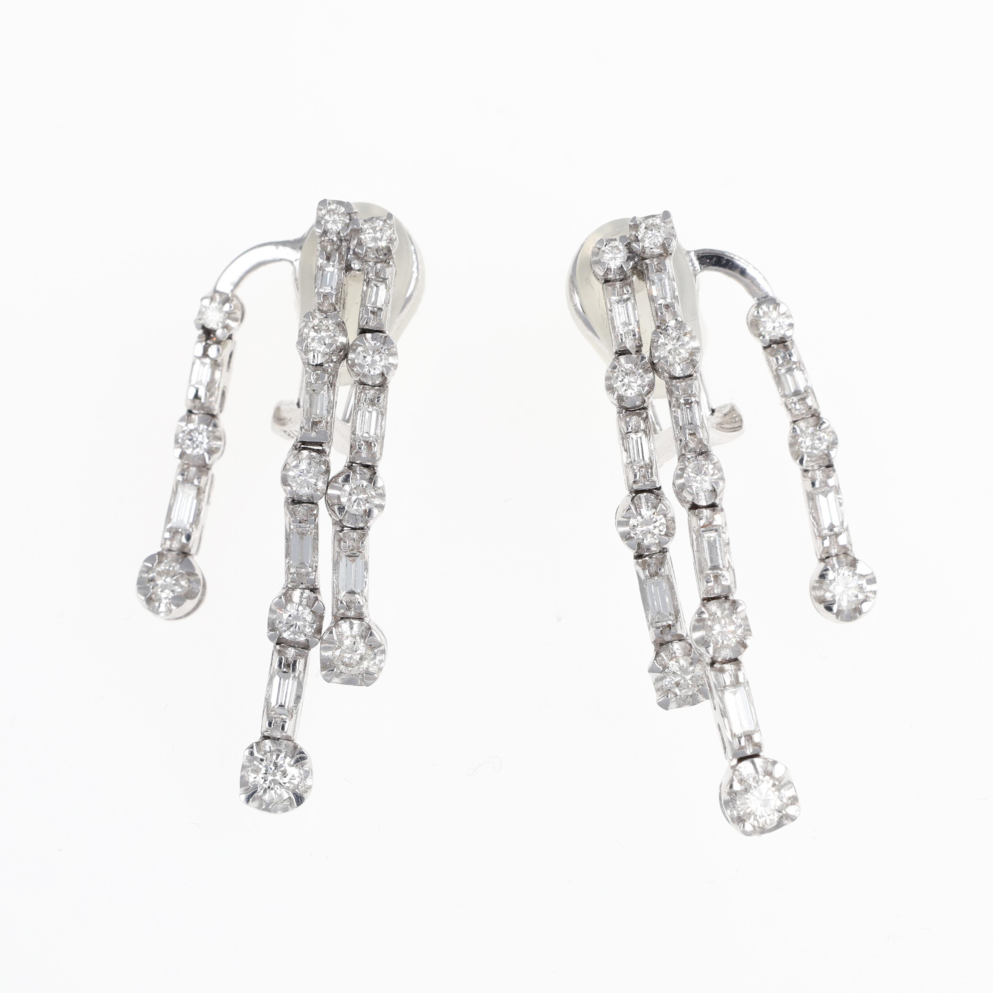A sophisticated pair of drop earrings crafted in 18K white gold, featuring three elegant dangling bars adorned with a stunning combination of brilliant and baguette-cut diamonds. With a total diamond weight of 1.87 carats, these earrings exude