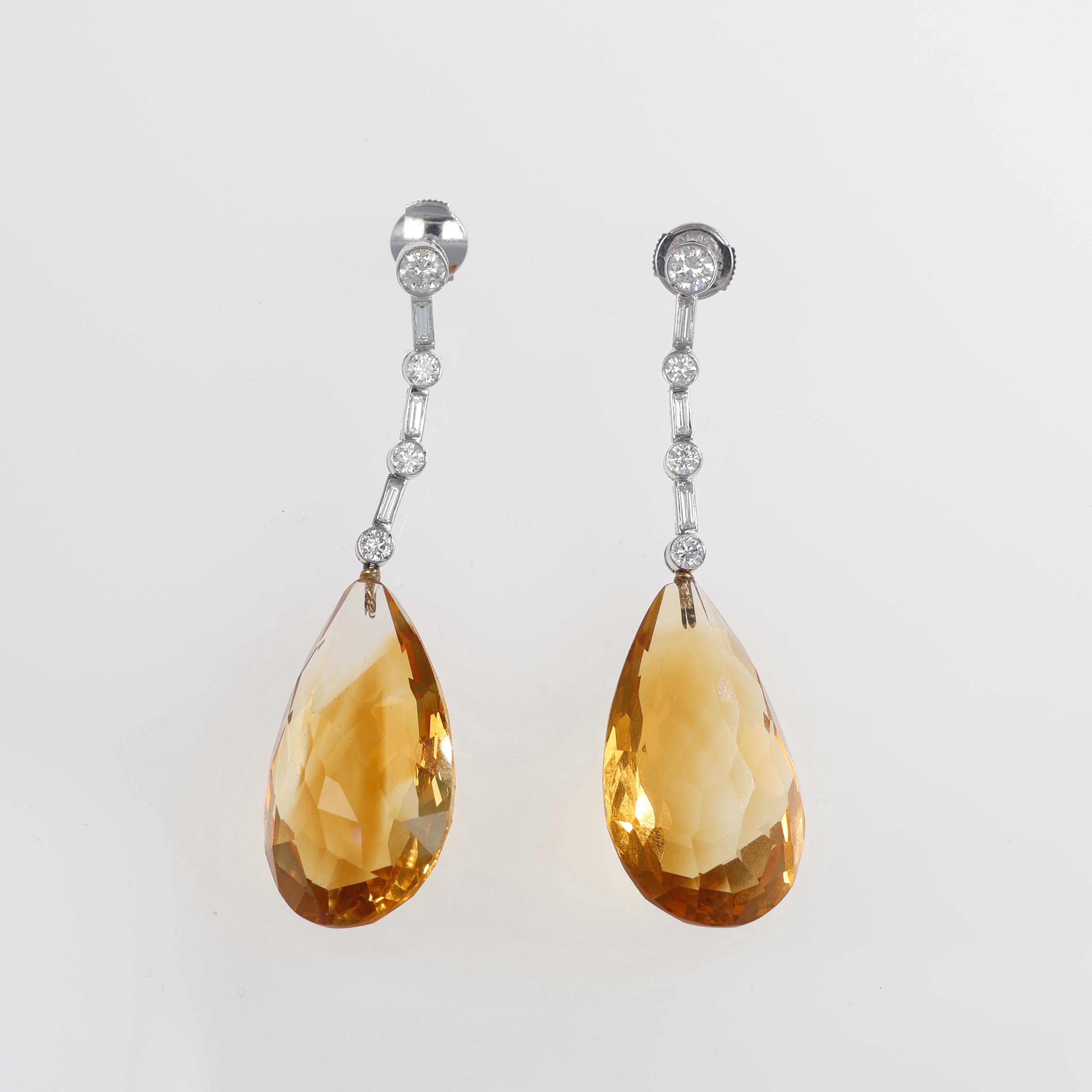 An elegant pair of 18K white gold drop earrings featuring two exquisite pear-cut natural yellow topaz gemstones, radiating warmth and brilliance. Suspended from a delicate line of sparkling round and baguette-cut white diamonds, these earrings offer