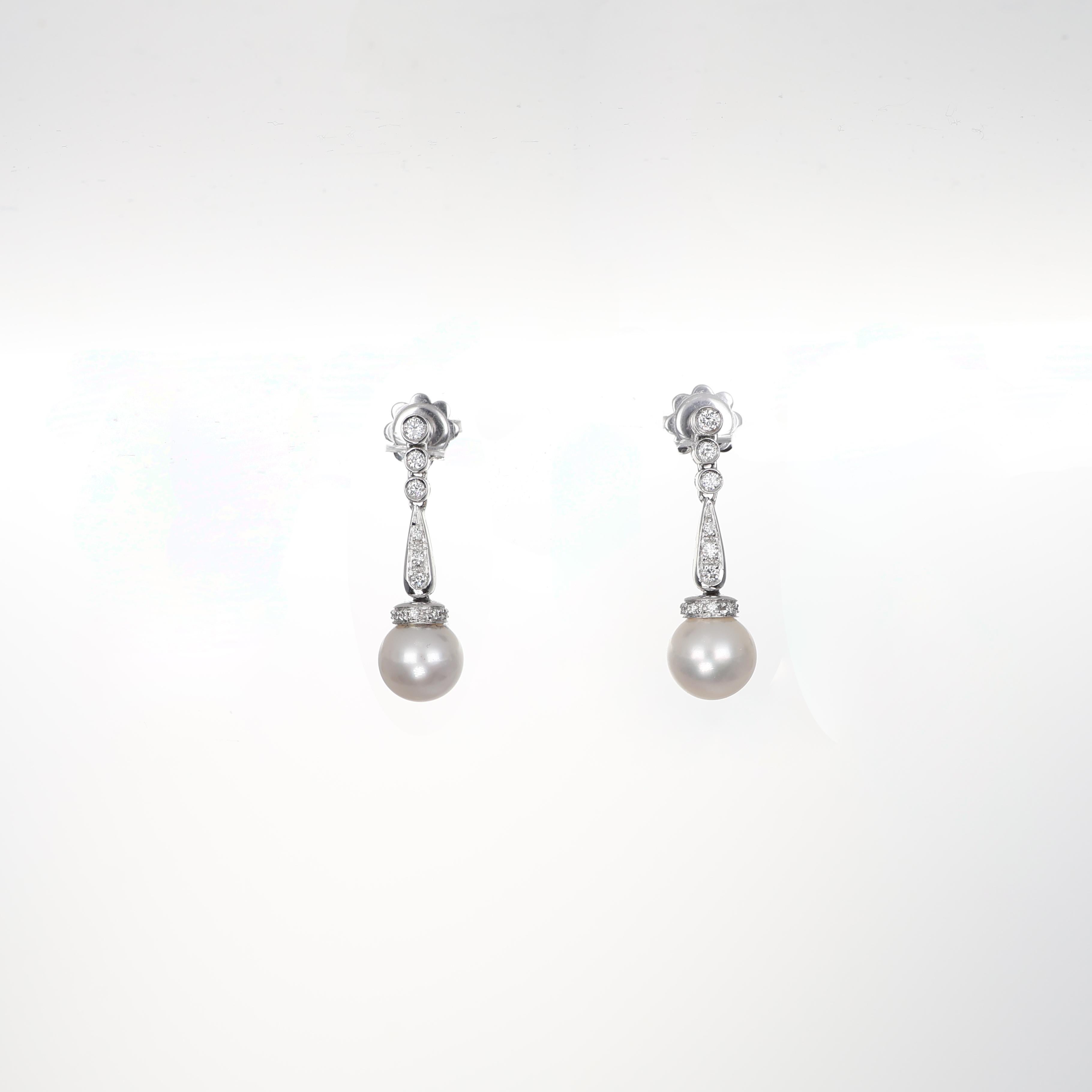 Refined and delicate, these drop earrings in 18K white gold feature luminous pearls suspended beneath a cascade of three brilliant-cut diamonds, culminating in an elegant diamond drop. A sophisticated blend of classic charm and contemporary