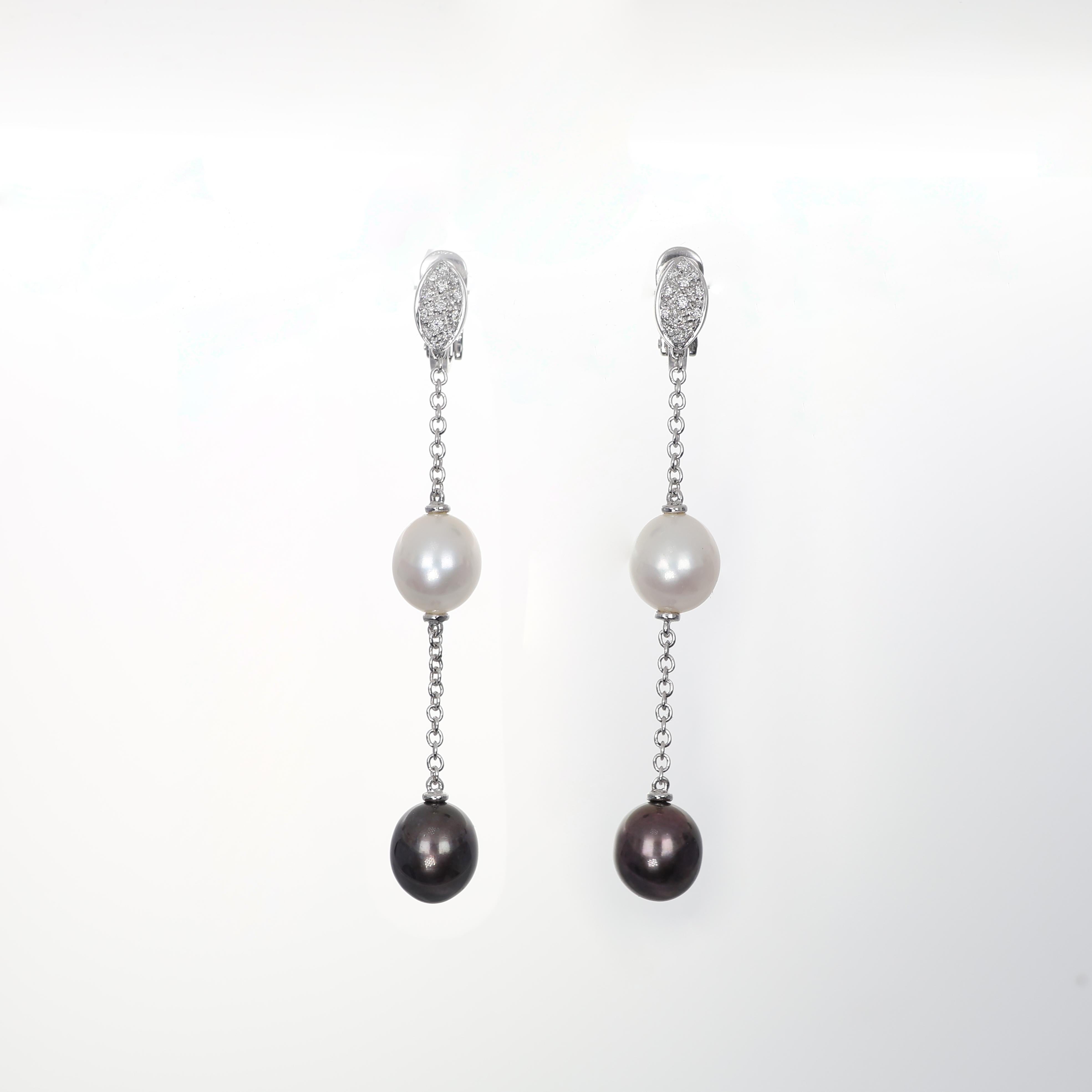 Elegant and refined, these 18K white gold drop earrings feature a delicate interplay of luminous white and black pearls suspended from a fine gold chain. The sparkling diamonds add a subtle brilliance, enhancing the contrast between the pearls. A