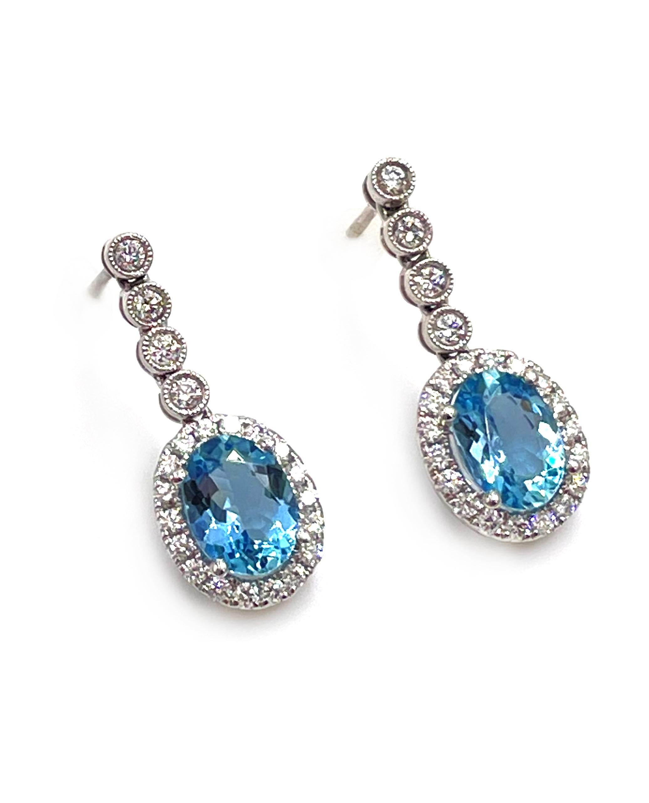 Pair of 18K white gold drop halo earrings with two oval shape aquamarines 1.88 carats total weight and 0.55 carats round diamonds.

- Diamonds are on average G/H color, SI1 clarity.
- Friction backs with medium size backings