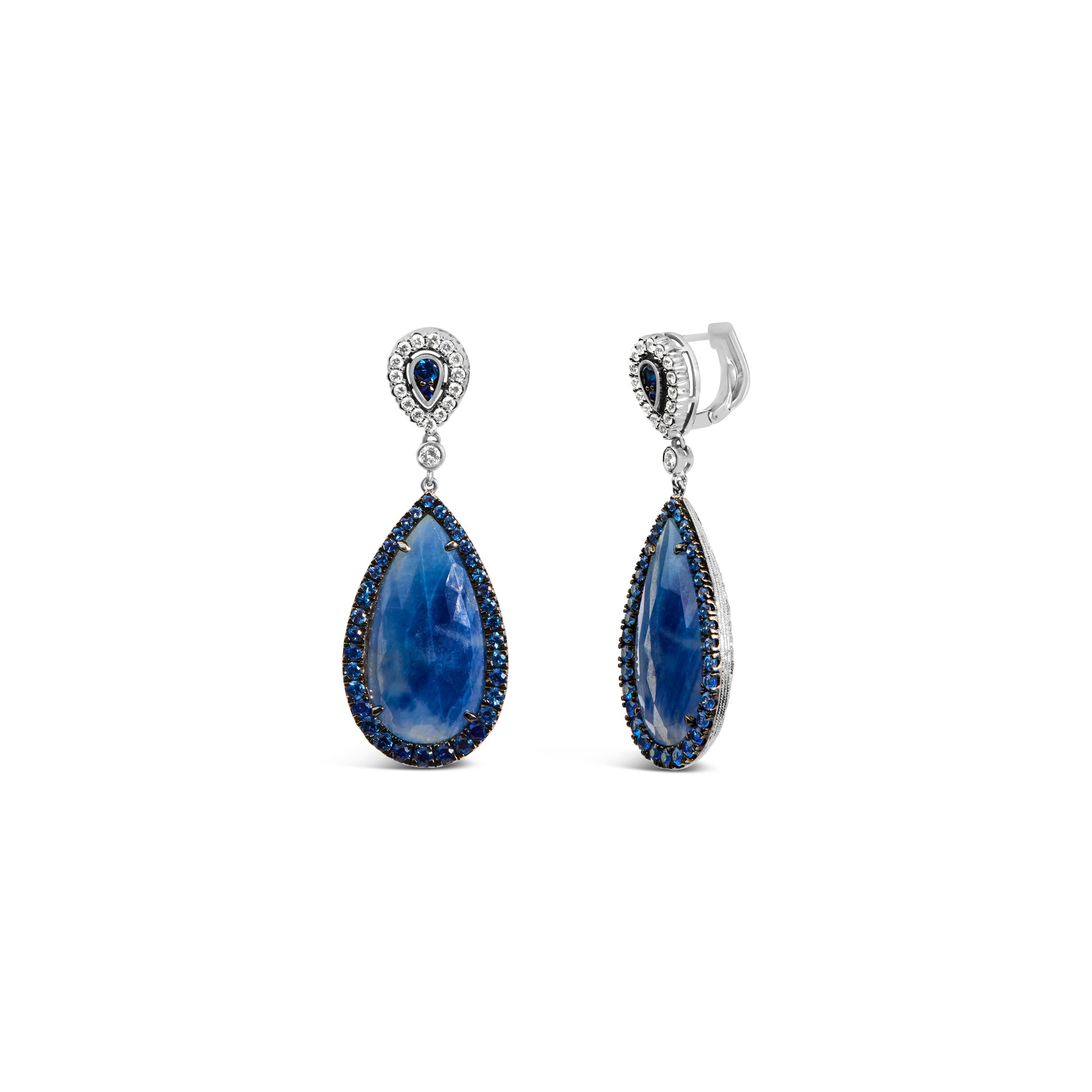 Adorn your ears with the epitome of elegance and artistry with this pair of 18K white gold earrings, each boasting a mesmerizing pear-shaped blue sapphire encased in a halo of shimmering diamonds. These natural sapphires, treated to enhance their