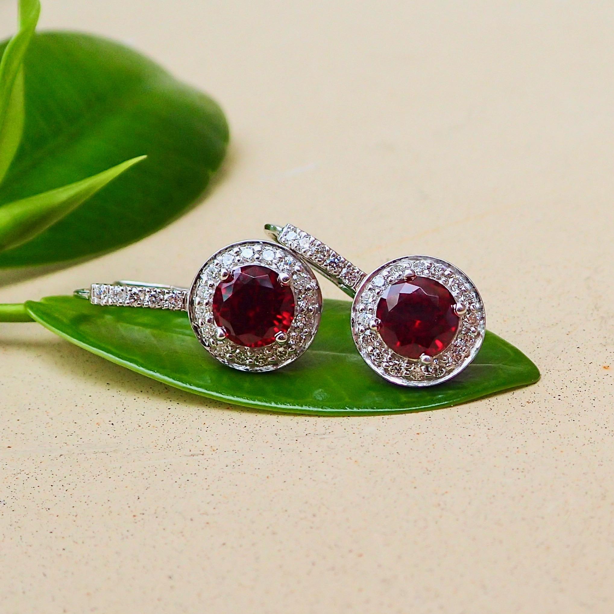 A pair of 18k white gold earrings contain two (2) Round Brilliant Cut Chatham-Created rubies that measure 6mm x 6mm and weigh a total of 2.23 carats with Clarity Grade VS and Fine Color with forty-two (42) Round Brilliant Cut diamonds that measure