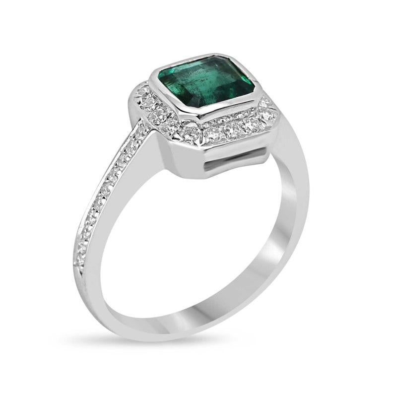 Capture the essence of everlasting love with this exquisite engagement ring. The heart of the design showcases a stunning 1.03-carat emerald cut emerald from Zambia, radiating an intense deep green hue with excellent clarity and luster. Embracing