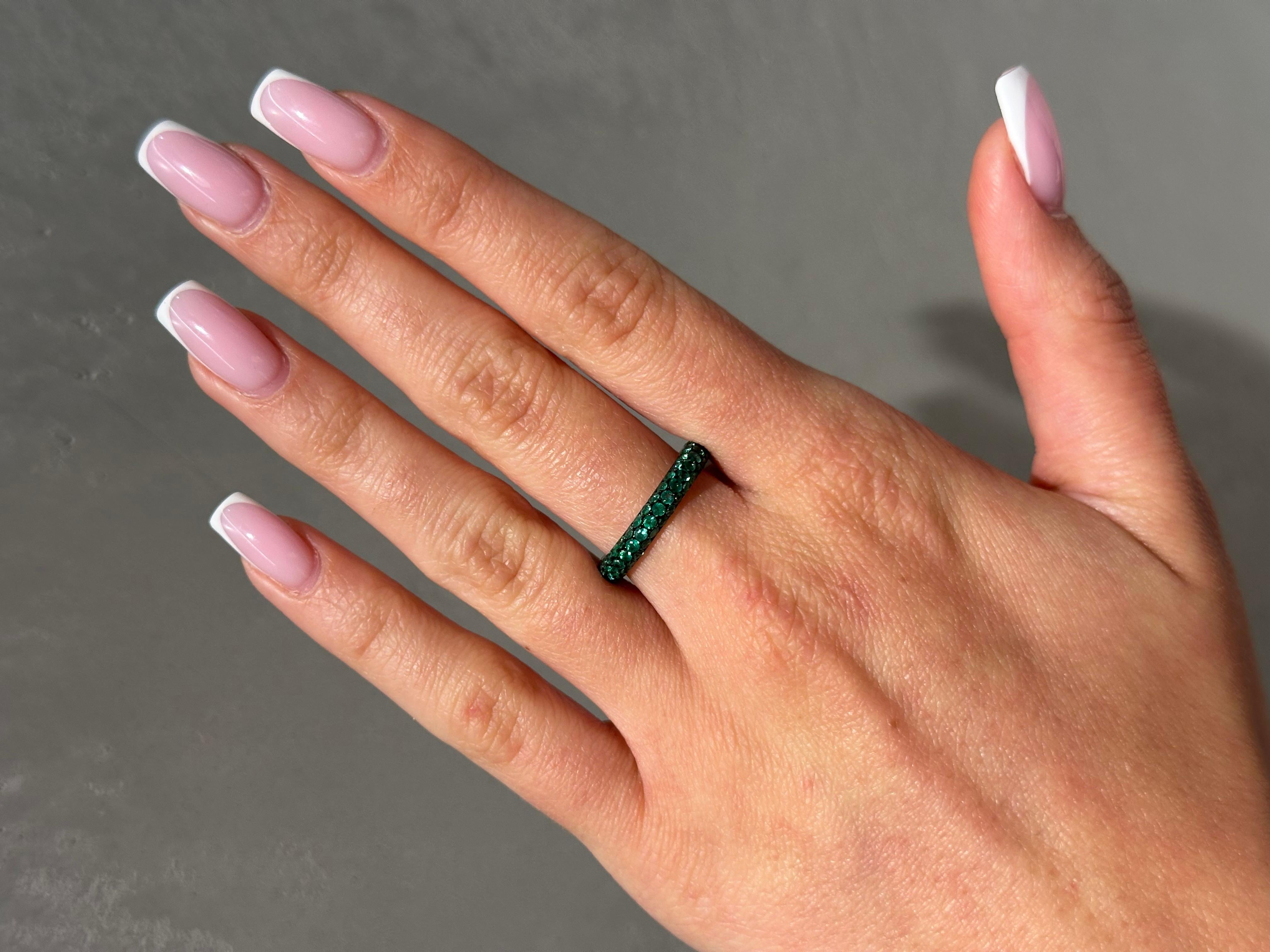 Cette superbe bague empilable est un chef-d'œuvre de luxe et d'élégance, en or blanc 18 carats, pesant 1,82 gramme. L'anneau poli, aux lignes épurées, constitue une toile de fond chic et discrète pour la star du spectacle : 2,12 carats d'émeraudes
