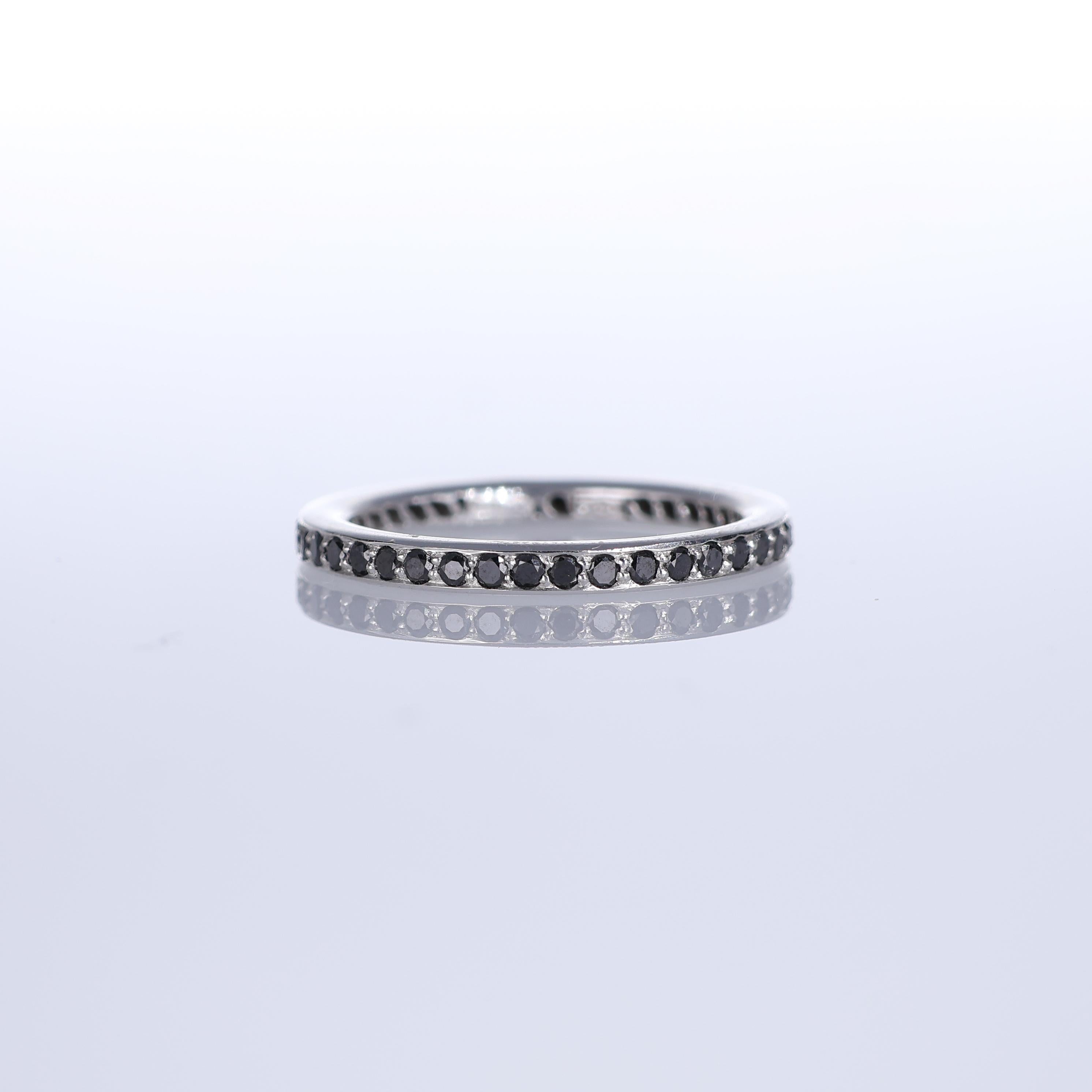 A sleek and modern eternity band crafted in 18K white gold, adorned with a continuous pavé of black diamonds totaling 0.64 carats. The refined setting enhances the deep contrast of the stones, creating a striking yet versatile piece. Ideal for