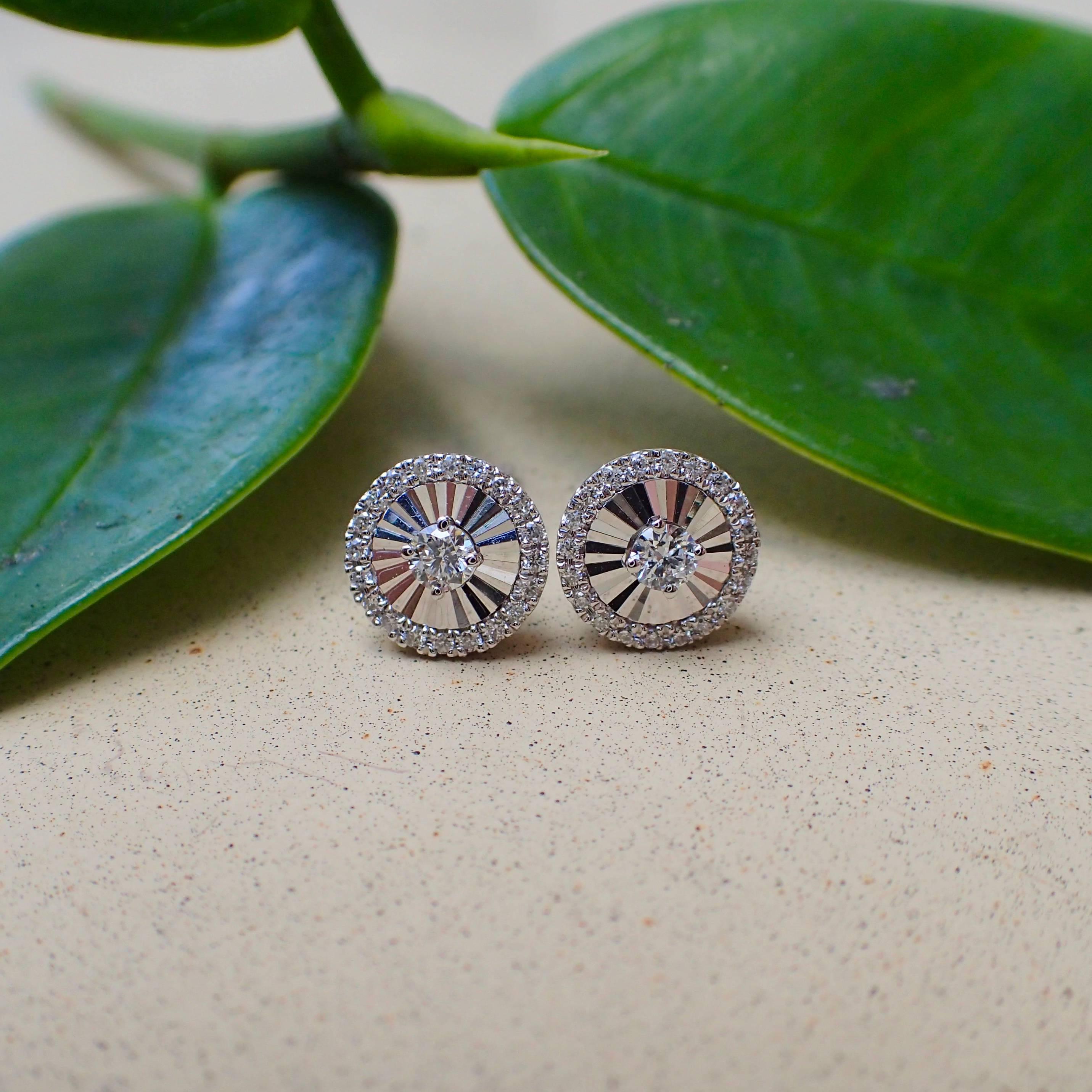 A pair of 18k white gold stud earrings are set with forty-two (42) Round Brilliant Cut diamonds with Clarity Grade VS and Color Grade G. The earrings have a machine-cut faceted fan pattern and have posts and clutches. The earrings weigh 1.9 grams