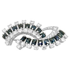 Broche « bypass » en or blanc 18 carats, sertie d'un saphir bleu taille française et de diamants ronds