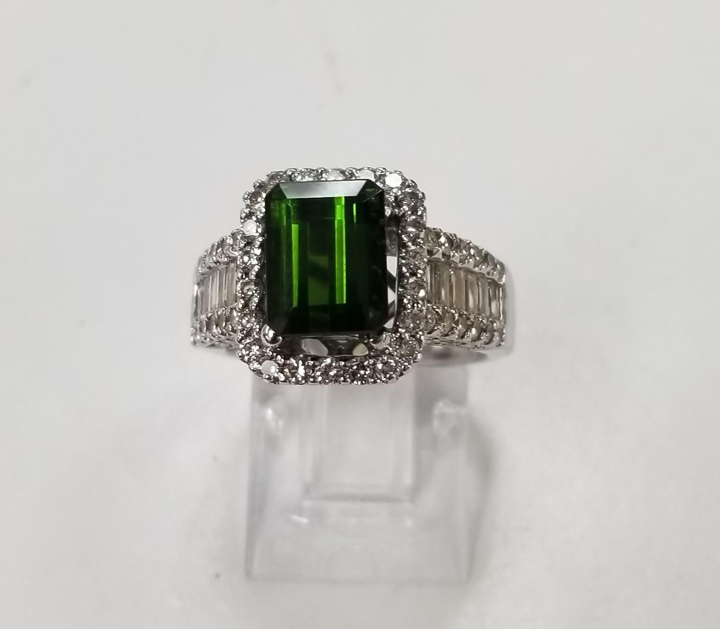 18k white gold Green Tourmaline and diamond halo ring, containing 1 green tourmaline of gem quality weighing 2.50cts. set with 12 baguette cut diamonds weighing .50pts. and 76 round full cut diamonds weighing .75pts. color 