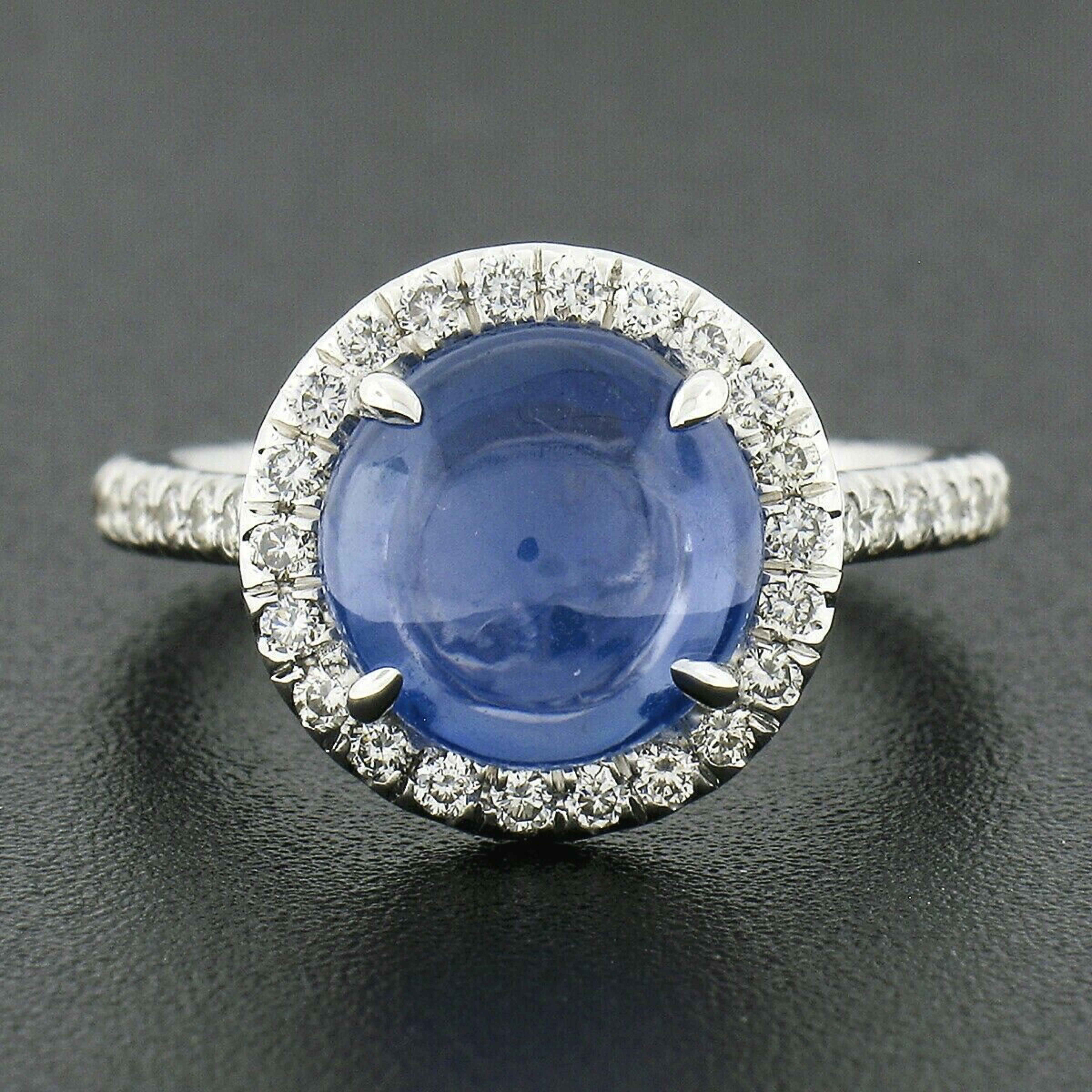 This gorgeous sapphire and diamond ring was crafted from solid 18k white gold. It features a Gubelin certified round cabochon cut sapphire neatly prong set at the center of a halo of round brilliant cut diamonds. The polished sapphire is certified